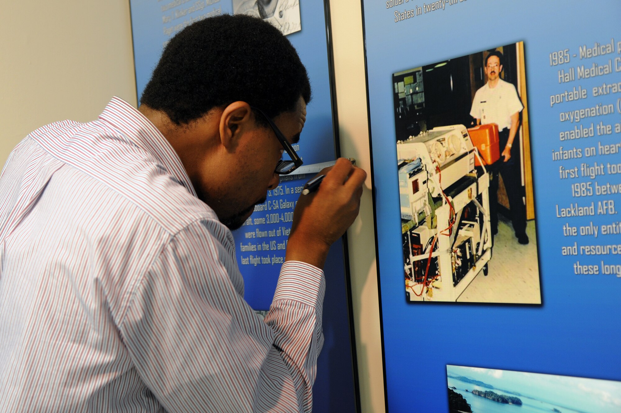 Ken Stewart, Air Force Medical Service historian assistant, measures the spacing between exhibit while installing the new AFMS Heritage Room at the Wilford Hall Ambulatory Surgical Center, Joint Base San Antonio-Lackland, Texas. The 11-panel exhibit highlights people, events, innovations, aircraft and facilities over the last 62 years. The new room is the first of its kind in the Air Force to focus on Air Force Medical Service heritage. (U.S. Air Force photo/Staff Sgt. Jason Huddleston)