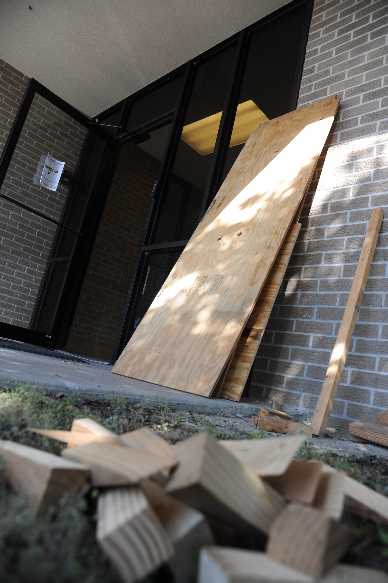 Boards sit near doors and windows for “hardening” on building 222 during a hurricane exercise May 21, 2014, at Keesler Air Force Base, Miss. Throughout the exercise, “Hurricane Danielle” brought severe thunderstorms, tornado strength winds, rain and hail damage to several base facilities.  The purpose of the exercise was to prepare Keesler for the upcoming hurricane season.  (U.S. Air Force photo by Kemberly Groue)