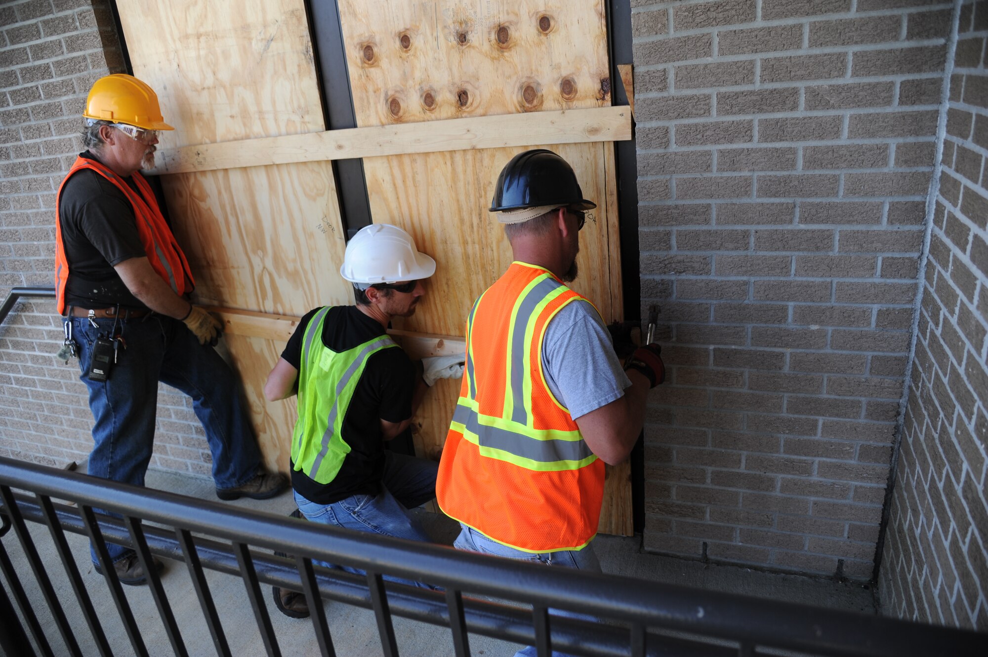 John Akins, Thomas Frisbie and Jeremy Railey, Pacific Architects and Engineers, board up windows and doors on building 222 during a hurricane exercise May 21, 2014, at Keesler Air Force Base, Miss. Throughout the exercise, “Hurricane Danielle” brought severe thunderstorms, tornado strength winds, rain and hail damage to several base facilities.  The purpose of the exercise was to prepare Keesler for the upcoming hurricane season.  (U.S. Air Force photo by Kemberly Groue)