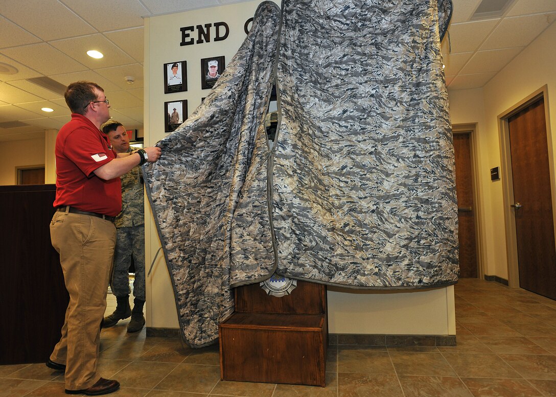 Retired Staff Sgt. Kristoffer Schnieder, 319th Security Forces Squadron patrolman, unveils the Defender Memorial at the 319th SFS headquarters building May 21, 2014, on Grand Forks Air Force Base, N.D. The Defender Memorial is dedicated to the lives of fallen Security Forces Airmen who have sacrificed their lives in the line of duty for the safety and protection of others. (U.S. Air Force photo/Senior Airman Xavier Navarro)