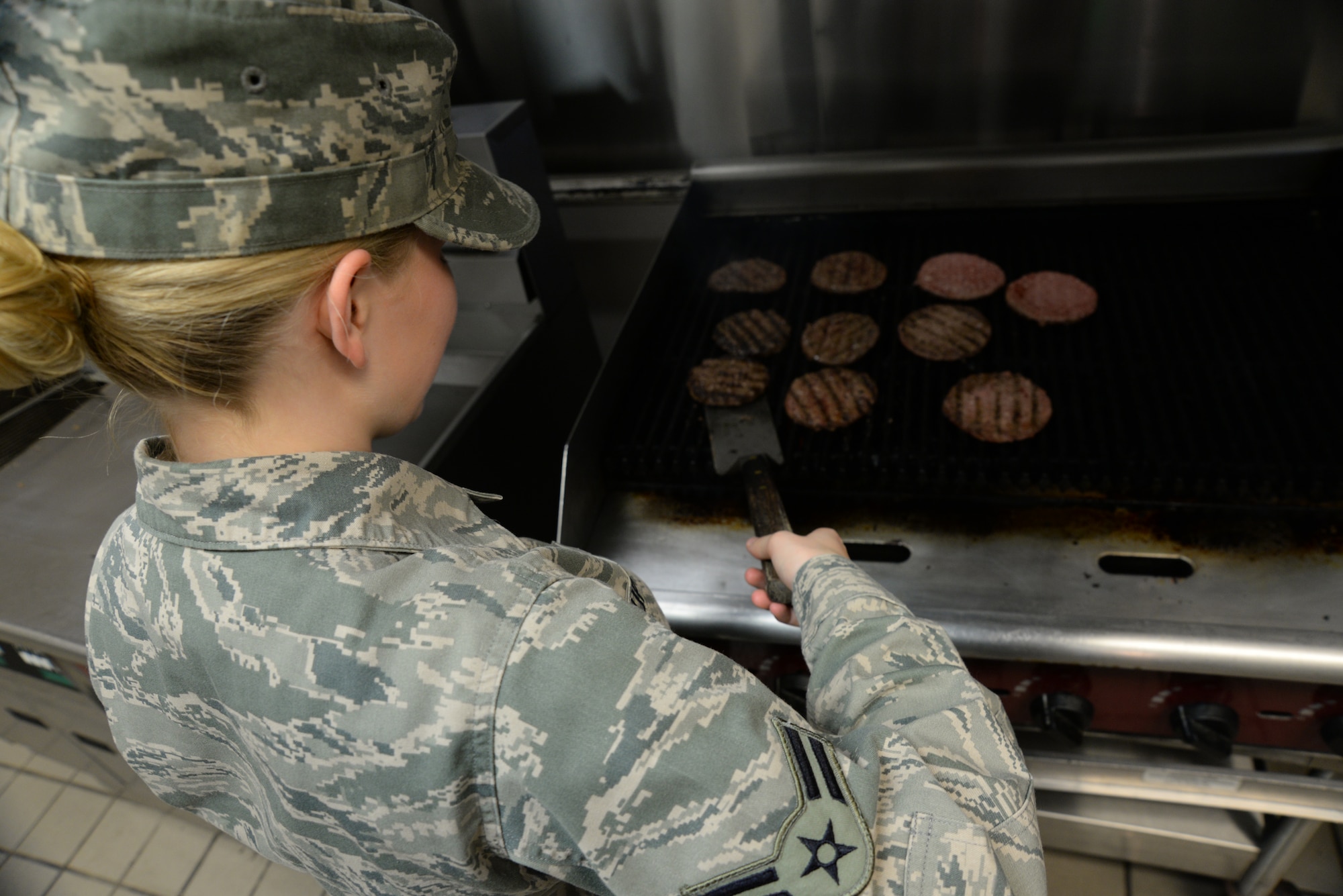 U.S. Air Force Airman 1st Class Crystal Upton, 20th Force Support Squadron food service specialist, flips a hamburger patty for the lunch rush at the Chief Master Sgt. Emerson E. William Dining Facility, May 21, 2014, Shaw Air Force Base, S.C.  The DFAC offers a snack line,  main line, salad bar, and a new potato bar. (U.S. Air Force by Airman 1st Class Michael A. Cossaboom/Released)