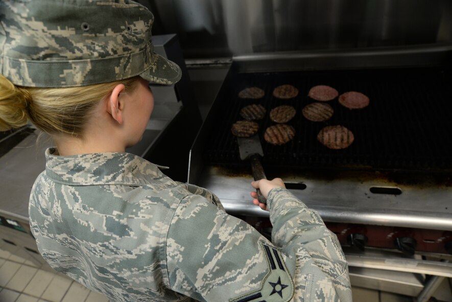 U.S. Air Force Airman 1st Class Crystal Upton, 20th Force Support Squadron food service specialist, flips a hamburger patty for the lunch rush at the Chief Master Sgt. Emerson E. William Dining Facility, May 21, 2014, Shaw Air Force Base, S.C.  The DFAC offers a snack line,  main line, salad bar, and a new potato bar. (U.S. Air Force by Airman 1st Class Michael A. Cossaboom/Released)