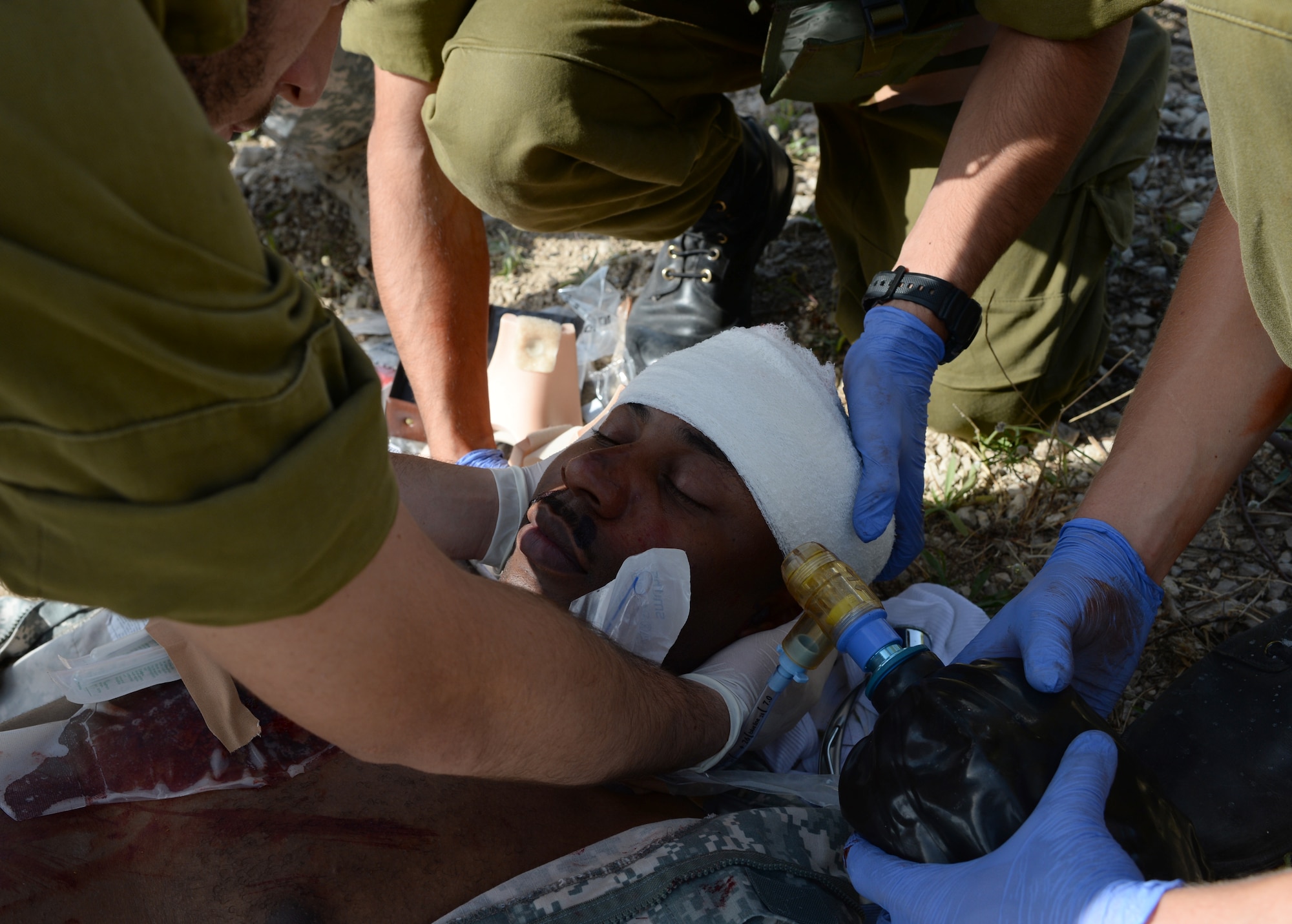 Three Israeli medics treat the simulated wounds on U.S. Army Staff Sgt. Willie Morgan, a generator mechanic assigned to the 10th Army and Missile Defense Command at Kaiserslautern, Germany, and Atlanta native, during a simulated medical evacuation as part of the Juniper Cobra 14 defense training exercise at Hatzor Air Base, Israel, May 20, 2014. Approximately 2,000 U.S. service members and civilians stationed in Europe and the United States traveled to Israel to participate in JC14 as a training audience or exercise evaluators.  (U.S. Air Force photo by Staff Sgt. Joe W. McFadden/Released)
