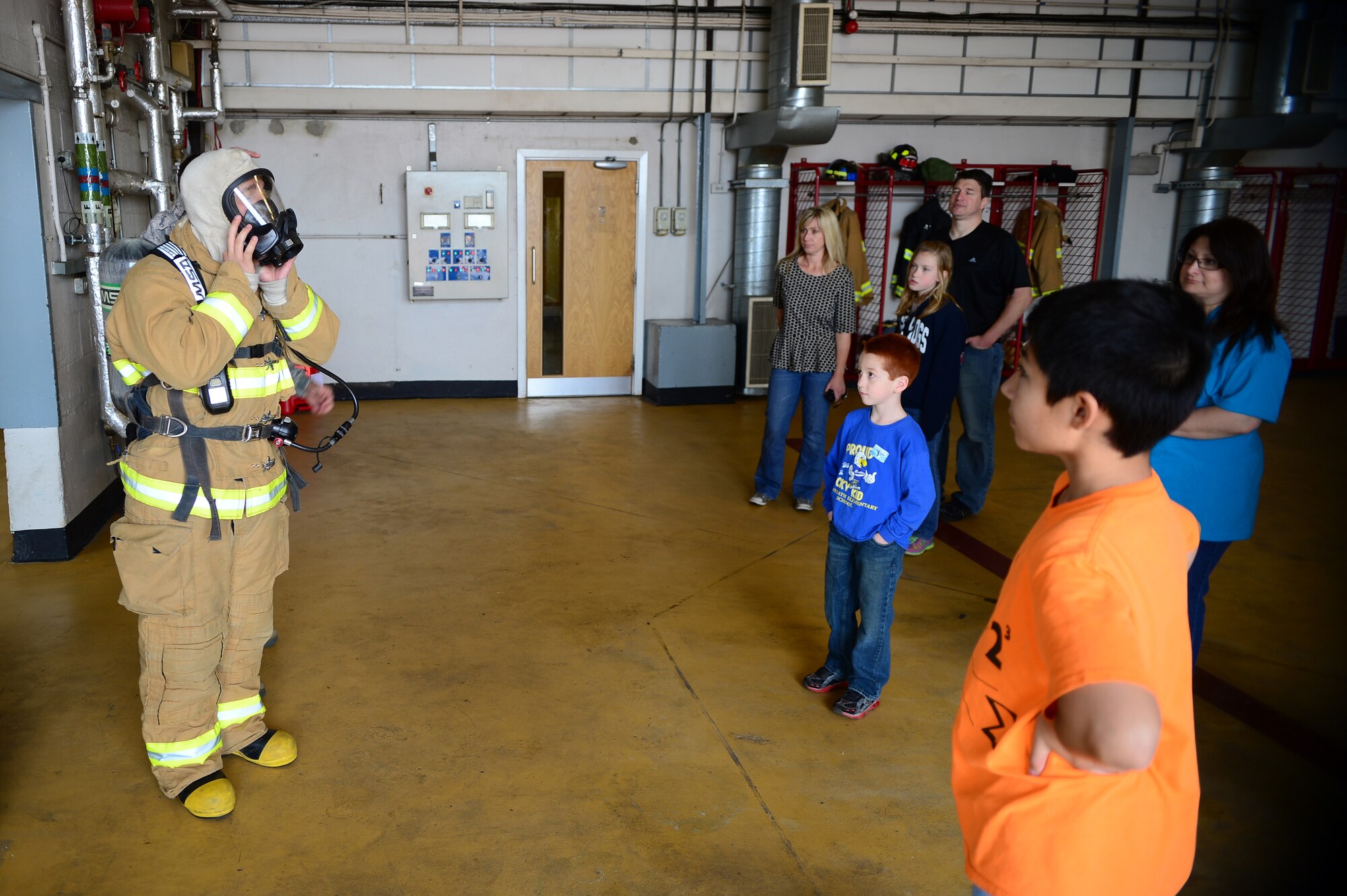 Airman 1st Class Karl Pischinger III, 48th Civil Engineer Squadron firefighter, dons his protective gear during Job Shadow Day at Royal Air Force Lakenheath, England, May 23, 2014. Job Shadow Day introduced students to a variety of professions, and gave them insight on different jobs in the Air Force. (U.S. Air Force photo by Staff Sgt. Emerson Nuñez/Released)