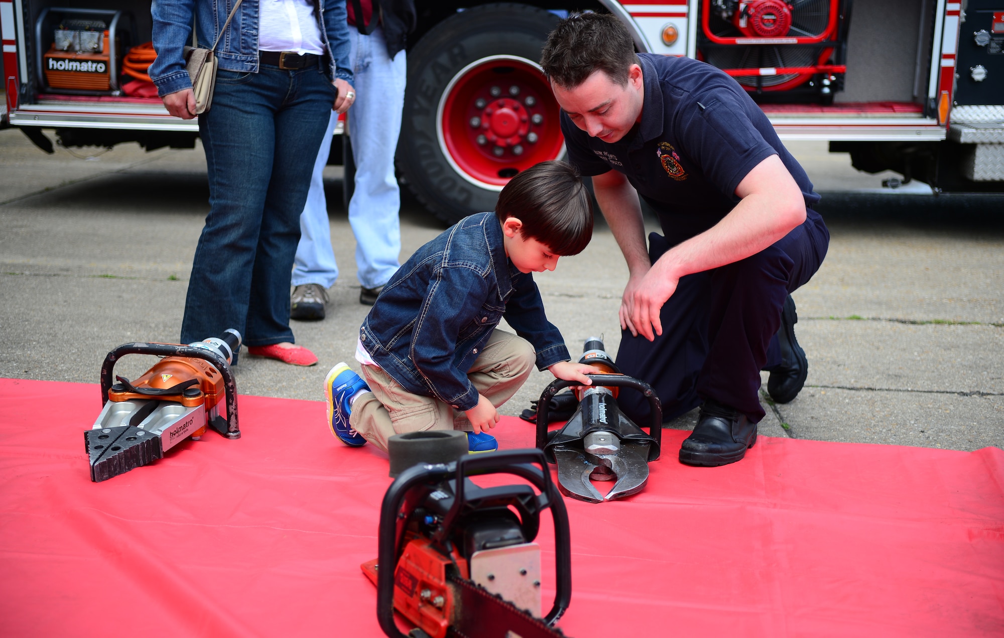 Mark Roberts, 48th Civil Engineer Squadron civilian firefighter, explains to William Sherwood, son of Tech. Sgt. William Sherwood, 48th Munitions Squadron NCO in charge of precision guided munitions support, about tools firefighters use in different scenarios during Job Shadow Day at Royal Air Force Lakenheath, England, May 23, 2014. Job Shadow Day provided students the opportunity to learn about different Air Force jobs and allowed hands-on experience in an interactive environment. (U.S. Air Force photo by Staff Sgt. Emerson Nuñez/Released)