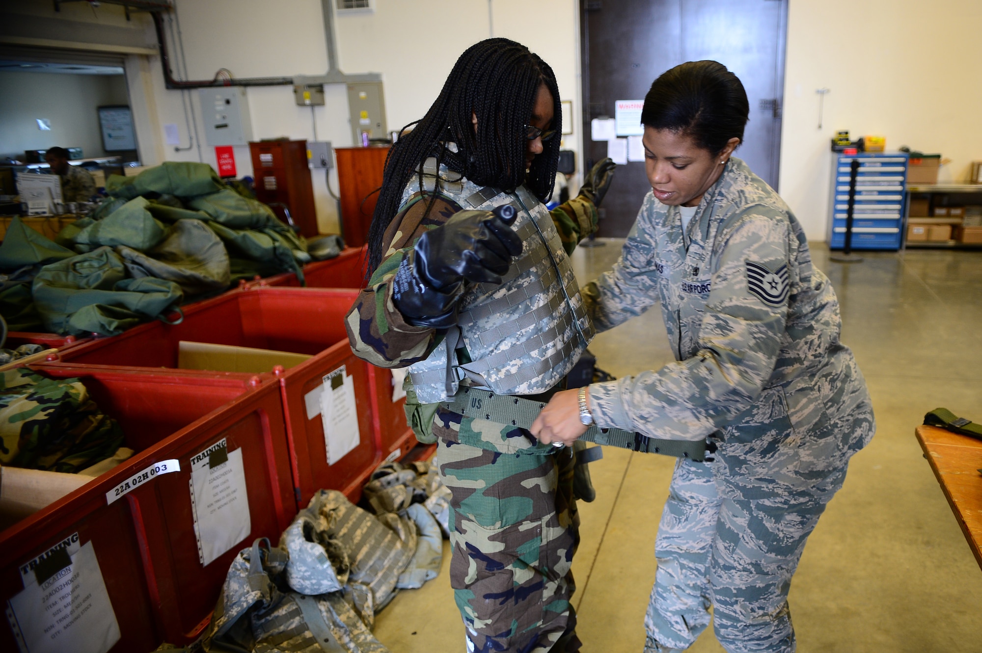 Tech. Sgt. Dawn Thomas, 48th Logistics Readiness Squadron NCO in charge of individual protective equipment, puts a web belt on her daughter, Gabriele Clavo, during Job Shadow Day at Royal Air Force Lakenheath, England, May 23, 2014. During the day, a variety of work centers across RAFs Lakenheath, Feltwell and Mildenhall were open to students to demonstrate military and civilian careers in action. (U.S. Air Force photo by Staff Sgt. Emerson Nuñez/Released) 