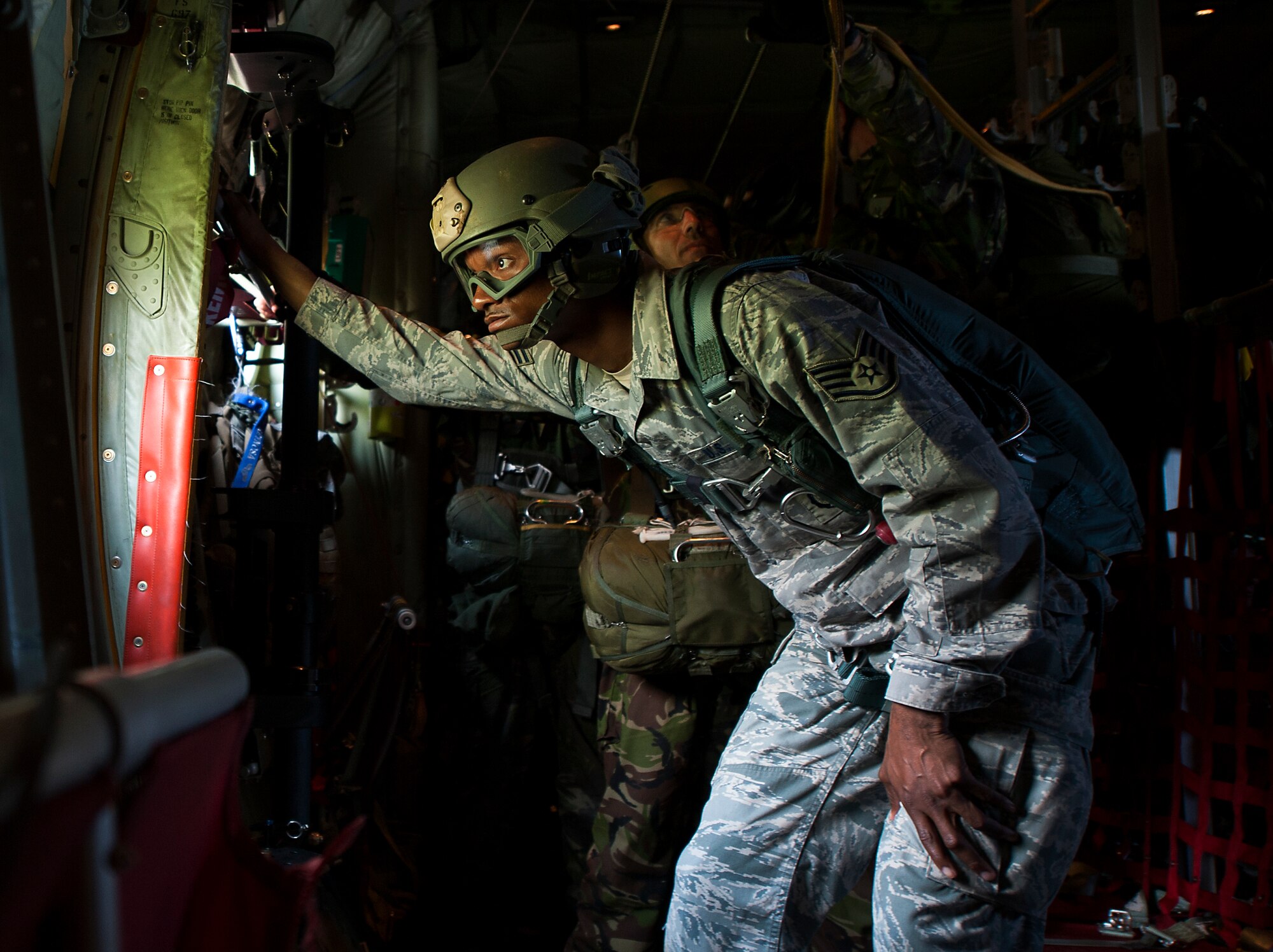 U.S. Air Force Staff Sgt. Cameron Riley, 435th Contingency Response Group jumpmaster, looks out the side door of a C-130J Super Hercules during Carpathian Spring 2014, above Campia Turzii, Romania, May 21, 2014. Riley, along with other jumpmasters, ensured the safety of service members as they exited the aircraft. (U.S. Air Force photo/Senior Airman Damon Kasberg)
