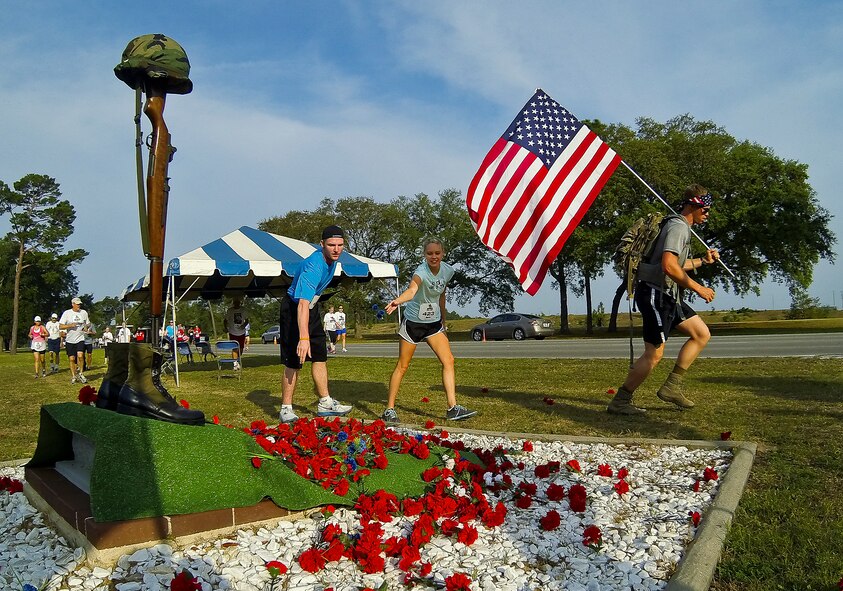 Runners toss carnations onto the All Veterans Memorial during the 29th annual Gate-to-Gate Run May 24 at Eglin Air Force Base, Fla. More than 1,200 people participated in the 4.4-mile race. (U.S. Air Force photo/Samuel King Jr.)