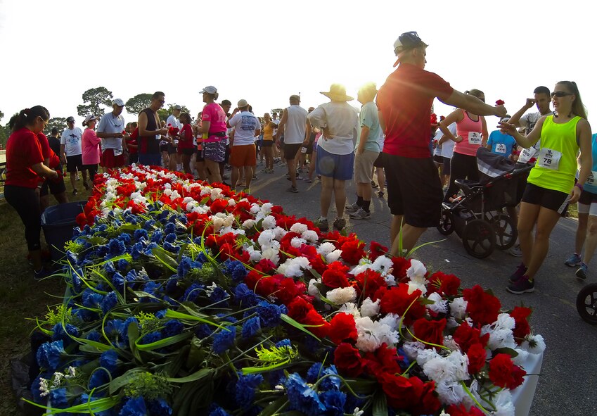 Volunteers hand out carnations as the sun rises over the 29th annual Gate-to-Gate Run May 24 at Eglin Air Force Base, Fla. More than 1,200 people participated in the 4.4-mile race. Many of the runners paid their respects by dropping off flowers in front of the All Veterans Memorial as they raced by. (U.S. Air Force photo/Samuel King Jr.)
