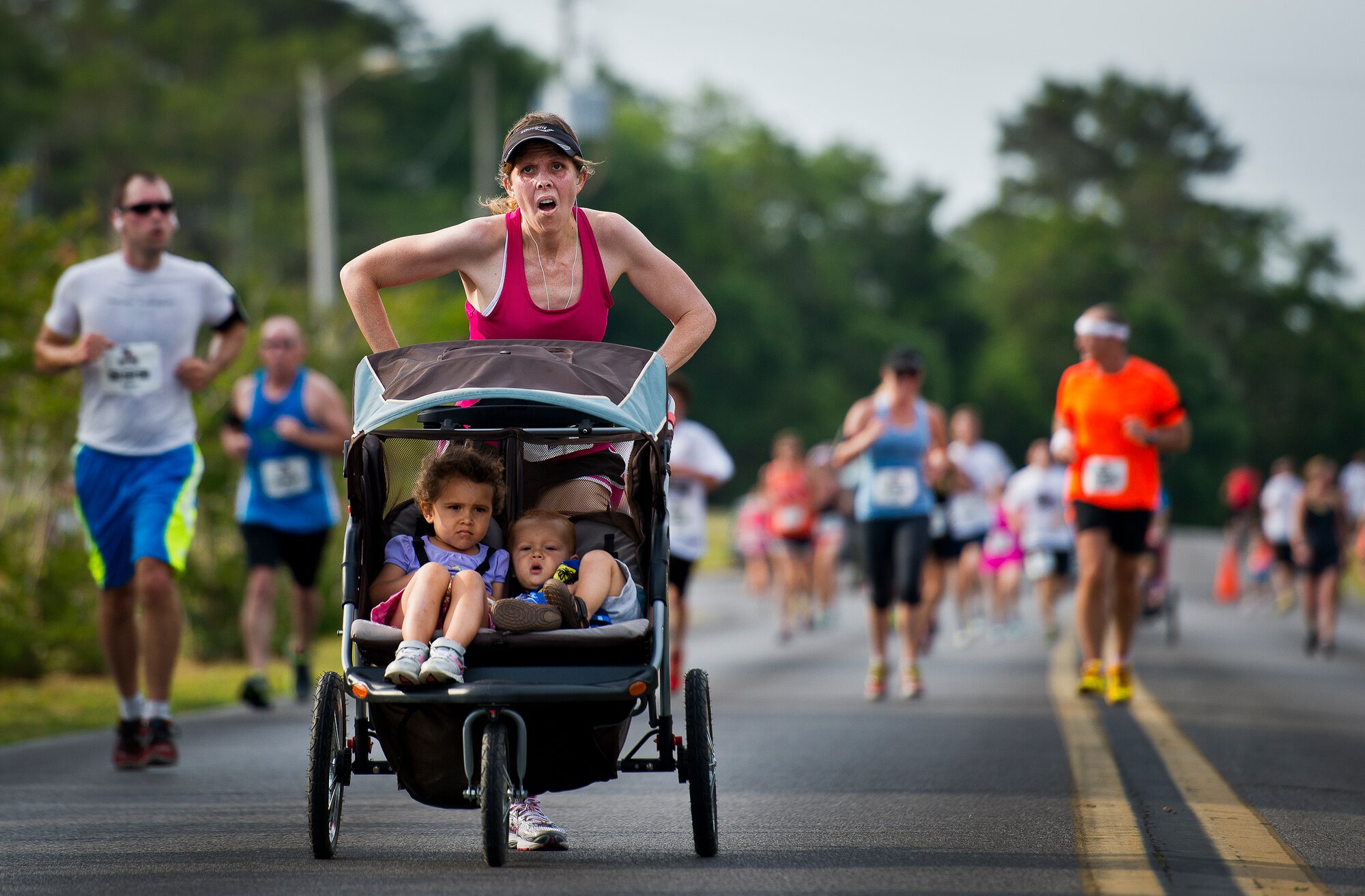 A mother pushes her two children toward the finish line of the 29th annual Gate-to-Gate Run May 24 at Eglin Air Force Base, Fla. More than 1,200 people participated in the 4.4-mile race. Many of the runners paid their respects by dropping off flowers in front of the All Veterans Memorial as they raced by. (U.S. Air Force photo/Samuel King Jr.)