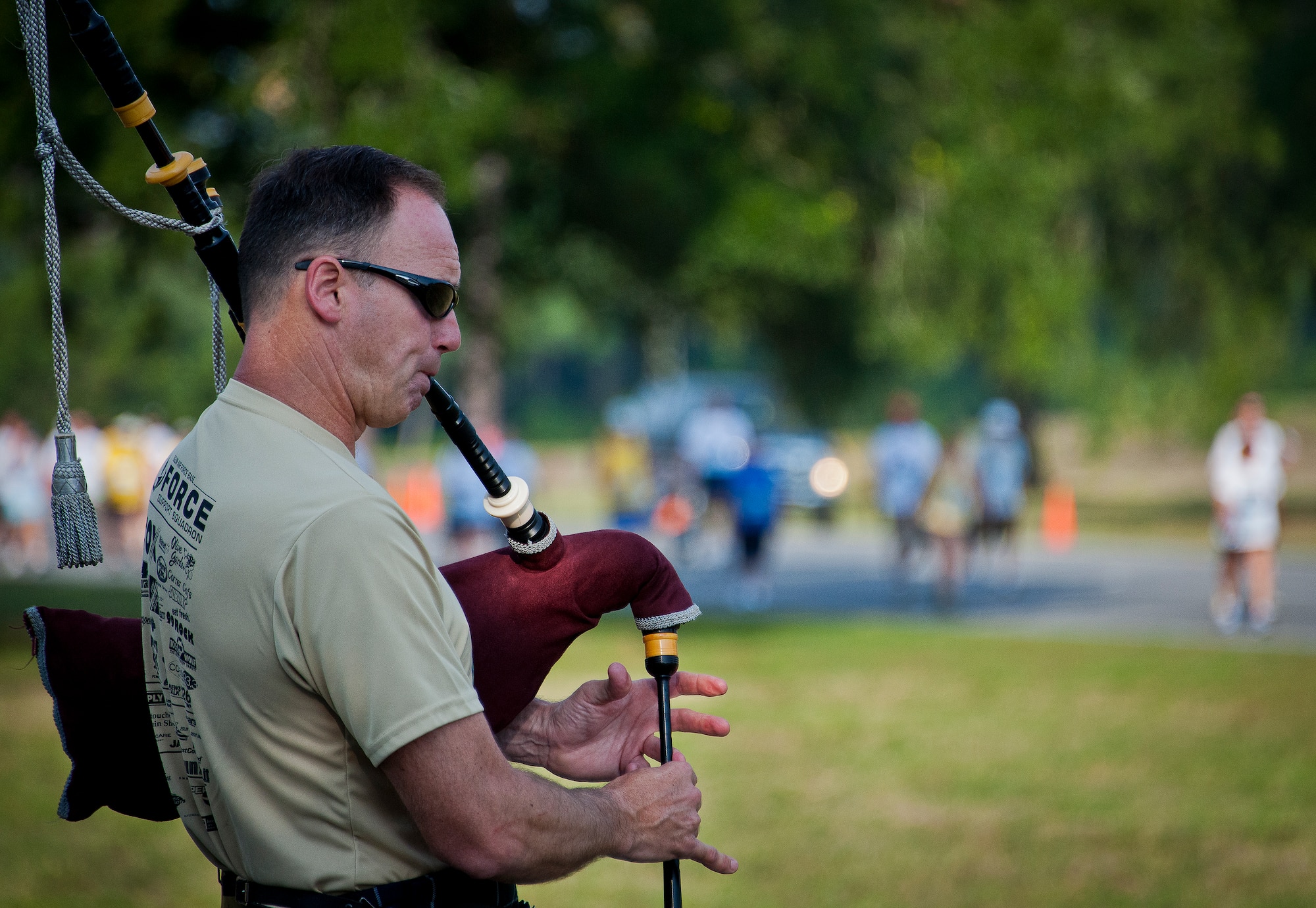 A bagpiper plays at the All Veterans Memorial as runners pass along Eglin Boulevard during the 29th annual Gate-to-Gate Run May 24 at Eglin Air Force Base, Fla. More than 1,200 people participated in the 4.4-mile race. Many of the runners paid their respects by dropping off flowers in front of the All Veterans Memorial as they raced by. (U.S. Air Force photo/Samuel King Jr.)