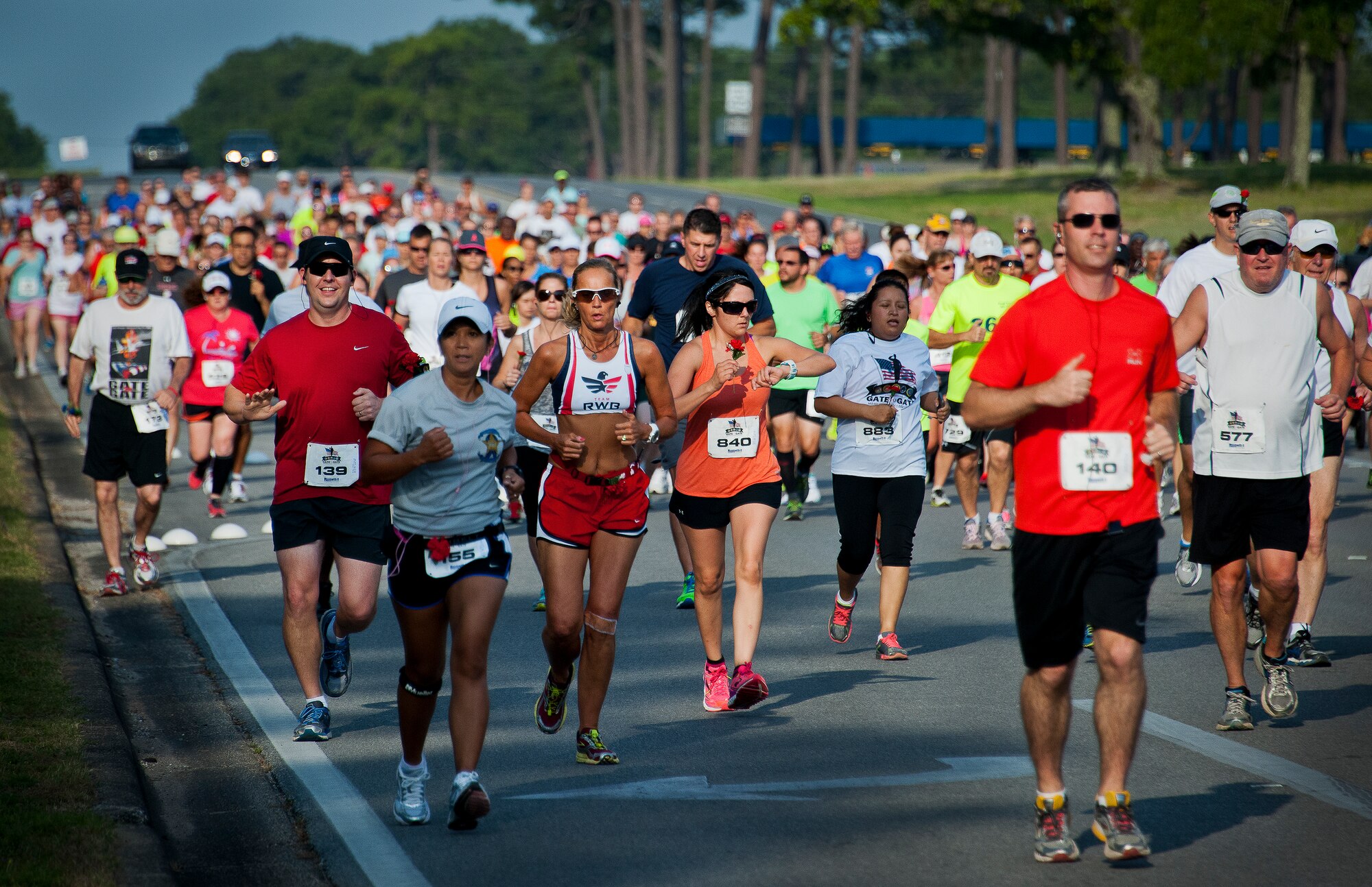 Runners pour down onto Eglin Boulevard during the 29th annual Gate-to-Gate Run May 24 at Eglin Air Force Base, Fla. More than 1,200 people participated in the 4.4-mile race. Many of the runners paid their respects by dropping off flowers in front of the All Veterans Memorial as they raced by. (U.S. Air Force photo/Samuel King Jr.)