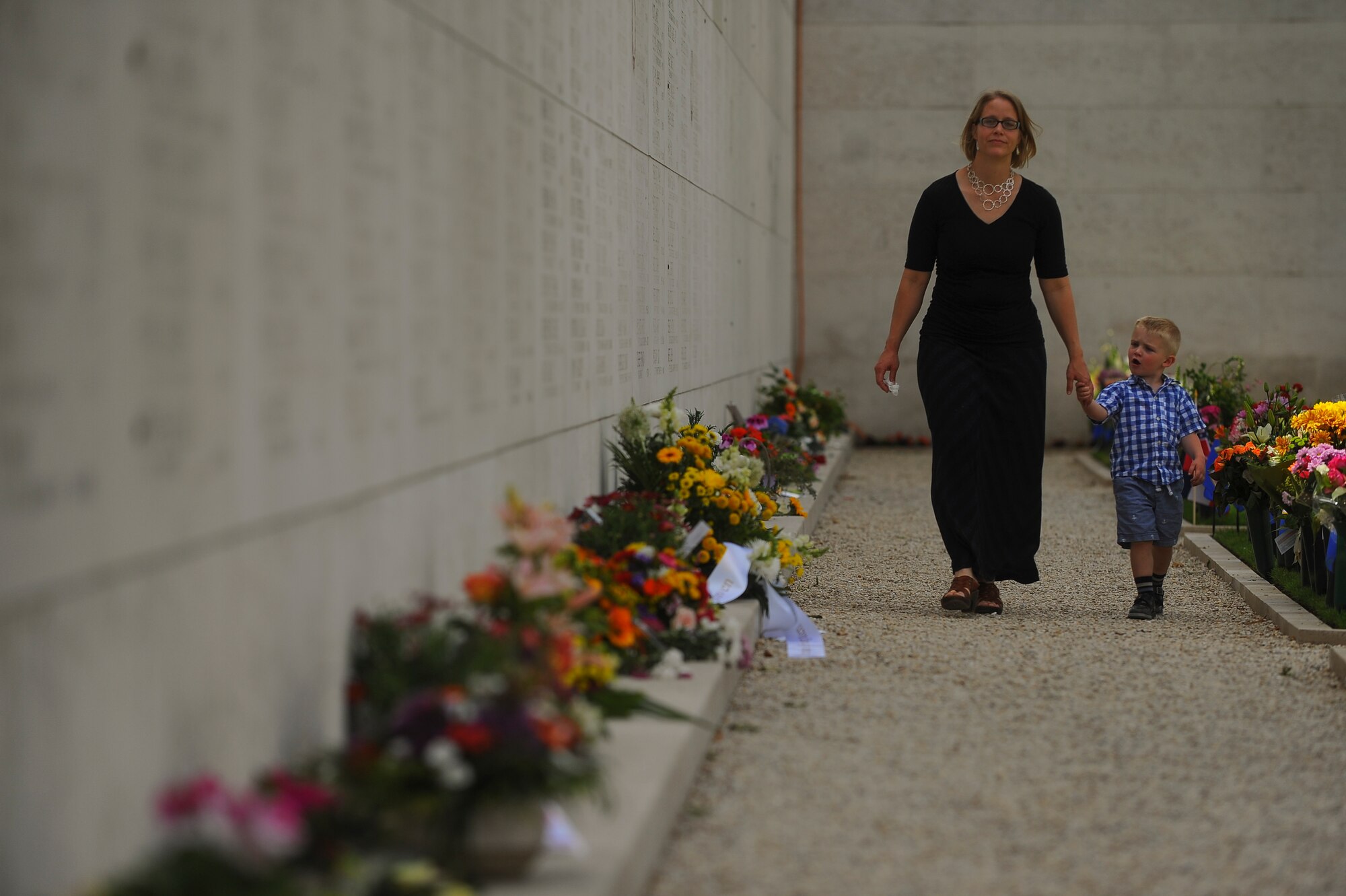 A mother and her child walk past the Wall of the Missing at the Netherlands American Cemetery prior to a Memorial Day ceremony May 25, 2014, Margraten, Netherlands. More than 1,000 names mostly from Operation Market Garden and the Battle of the Bulge are marked on the wall. (U.S. Air Force photo by Senior Airman Rusty Frank/Released)