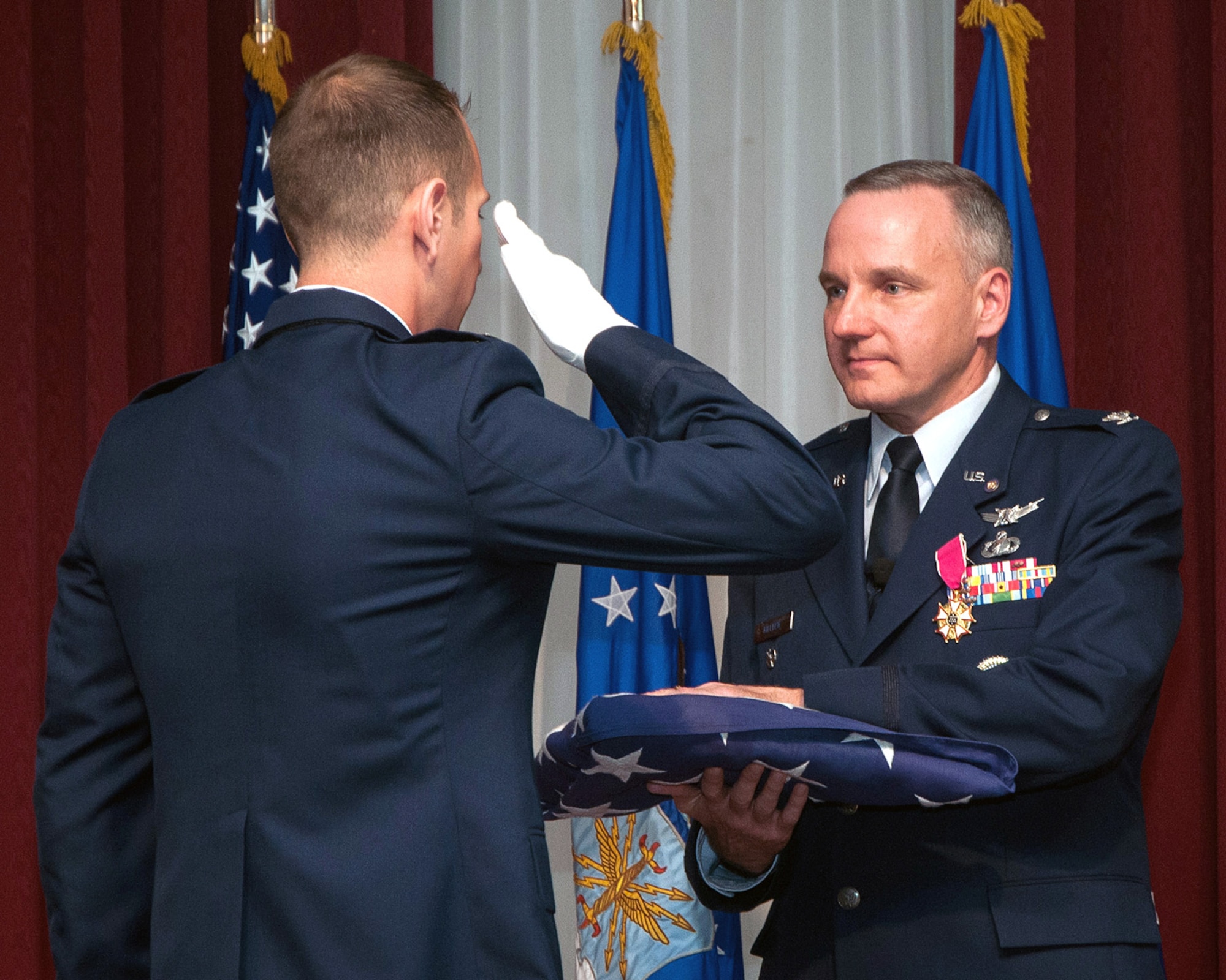 HANSCOM AIR FORCE BASE, Mass. – Col. Thomas J. Killeen, Airspace Mission Planning Division chief, is presented a flag by Capt. Scott Dotto during a retirement ceremony at the Minuteman Commons May 16. Killeen is retiring after 25 years of service, which included three tours of duty at Hanscom AFB. (U.S. Air Force photo by Mark Herlihy)