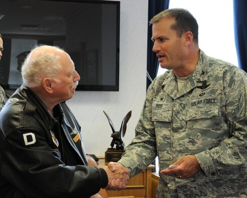 Joe Urice, left, a World War II veteran, shakes hands with U.S. Air Force Col. Kenneth T. Bibb Jr., 100th Air Refueling Wing commander, after Bibb presented a coin to Urice during a base visit May 22, 2014, on RAF Mildenhall, England. Urice served from December 1944 to November 1945 with the 100th Bombardment Group as a B-17 Flying Fortress tail-gunner. He visited the U.K. with his family and members of the 100th Bomb Group Foundation. Bibb spent time talking with Urice and they shared stories and accounts of their time at various stations. (U.S. Air Force photo by Gina Randall/Released)
