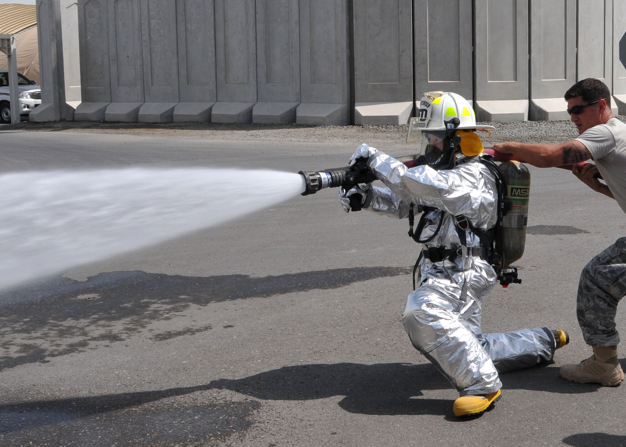 Air Force Tech. Sgt. Robin Ottmo, a member of the 380th Air Expeditionary Medical Group’s preventative medicine flight, operates a fire hose during the firefighter challenge obstacle course conducted by the fire department at fire station one in an undisclosed location on May 21, 2014. U.S. Air Force photo by Senior Master Sgt. Eric Peterson/Released)