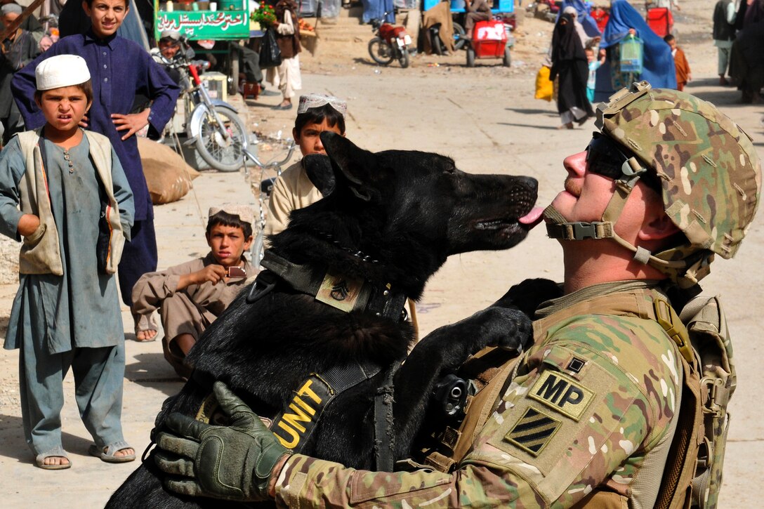 U.S. Army Sgt. Adam Serella bonds with his military working dog, Nero, as children look on during Operation Clean Sweep in Kandahar City in Afghanistan's Kandahar province, Oct. 3, 2012. Serella, a narcotics patrol detector dog handler, is assigned to the 3rd Infantry Division.  
