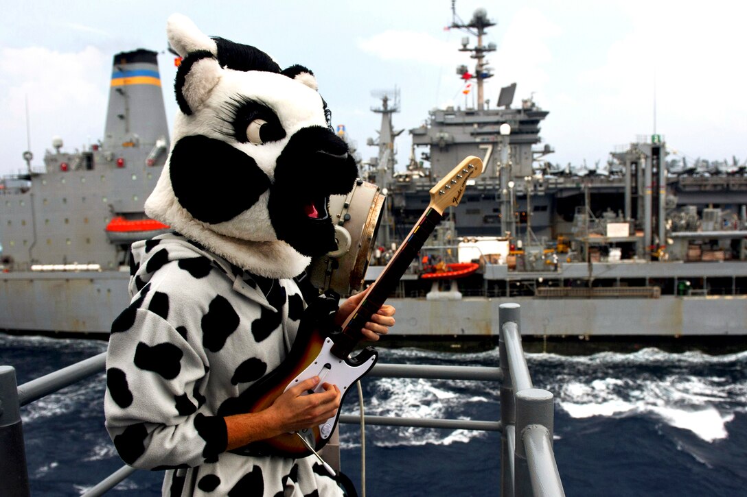 Scrub the Cow plays his guitar for the crew of the Military Sealift Command fleet replenishment oiler USNS Pecos from the guided-missile cruiser USS Cowpens during a replenishment operation in the Philippines Sea, Oct. 2, 2012. The Cowpens is part of the George Washington Carrier Strike Group based in Yokosuka, Japan.  
