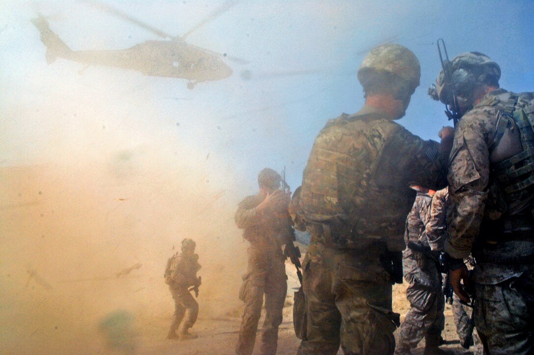 Coalition forces brace against the wind from a U.S. Army UH-60 Black Hawk helicopter near Bagh in Afghanistan's Zabul province, Aug. 30, 2012.  

