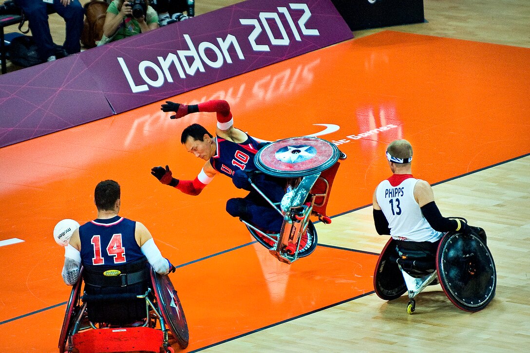 William Groulx, center, U.S. wheelchair rugby captain and retired Navy sailor, falls after a member of the British team crashes into him at the basketball arena during the 2012 Paralympic Games in London, Sept. 5, 2012.  
