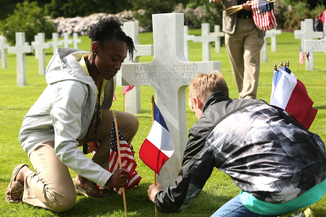 Volunteers including Marines, familly members and grounds keepers placed French and American flags in front each of the 2,289 grave markers on Saturday prior to the Belleau Wood memorial. United States Marines and their French counterparts gathered at Aisne-Marne American Cemetery May 25 to celebrate Memorial Day, and to mark the 96th anniversary of the historic Battle of Belleau Wood. The event was held in the memorial cemetery which lies adjacent to the historic grounds of Belleau Wood and featured the laying of wreathes, a firing of volleys, the playing of "TAPS," raising of the American and French national colors, and a concert by the French and Marine Corps military bands. The mayor of the village of Bellau along with other military officers and officials representing the U.S. and France were present along with hundreds of locals and visitors from around the world. Participating units from the U.S. Marines included 5th Marine Regiment, the Wounded Warrior Regiment and Marine Forces Europe and Africa. French units that participated in the ceremony included the 21st Marine Infantry Regiment and the Musique Principale des Troupes de Marines.