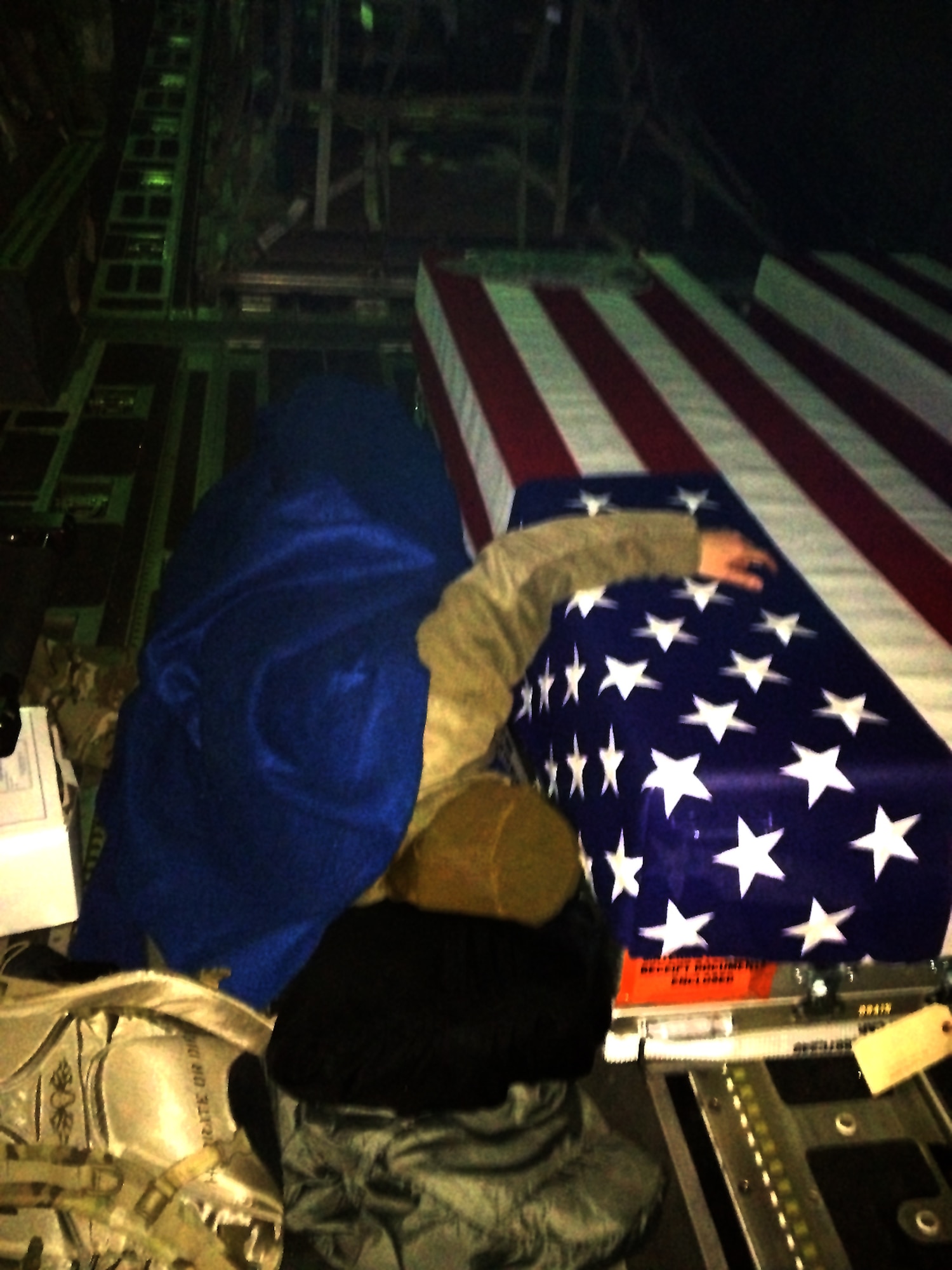 Capt. Dana Lyon lies next to her husband's transfer case as he is brought back to the states from Afghanistan. The Air Force named the service's newest pre-positioning vessel after Dana's husband, Capt. David Lyon, who died Dec. 27, 2013, in Kabul, Afghanistan, when a vehicle-born improvised explosive device was detonated near his convoy.  (Courtesy photo/Lyon family)
