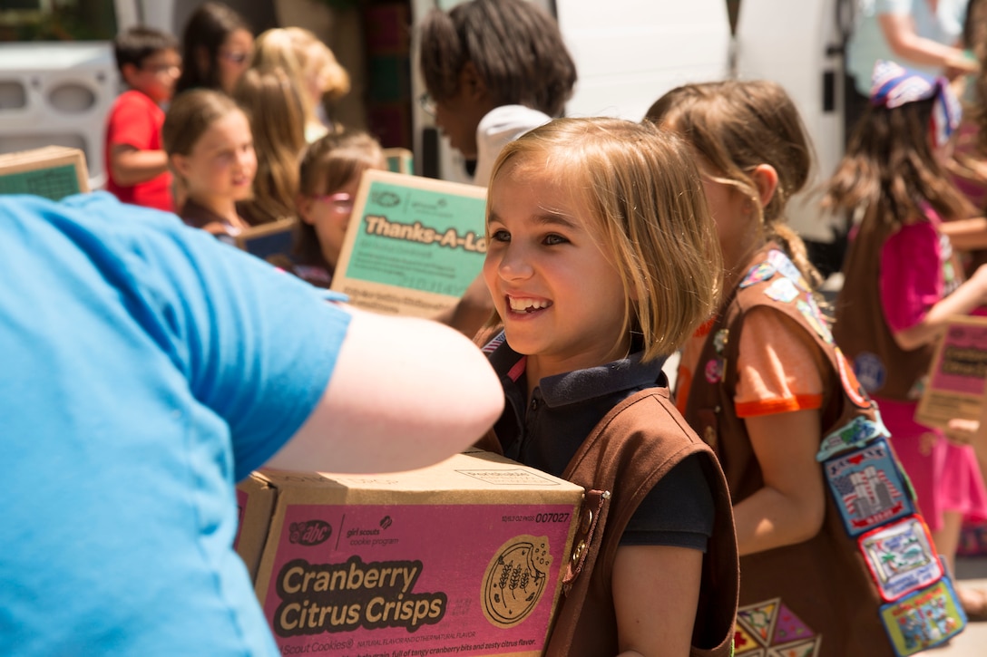 A Girl Scout passes a box of cookies to donate to the USO of North Carolina in Jacksonville during Operation Cookie Drop, May 22. The USO will use the cookies for homecomings, deployments and other events for service members and their families.