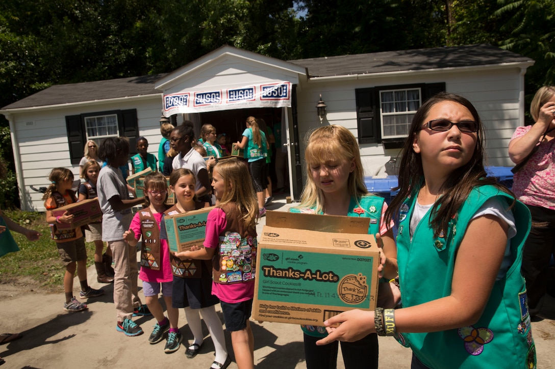 Girl Scouts pass boxes of cookies to each other to donate to the USO of North Carolina in Jacksonville during Operation Cookie Drop, May 22. The USO will use the cookies for homecomings, deployments and other events for service members and their families.