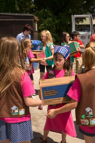 A Girl Scout passes a box of cookies to donate to the USO of North Carolina in Jacksonville during Operation Cookie Drop, May 22. The USO will use the cookies for homecomings, deployments and other events for service members and their families.