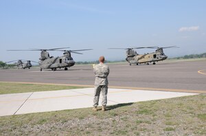 U. S. Army Lt. Col. Ernest Irvin, 1-228th Aviation Regiment commander, watches as two CH-47D Chinooks prepare to take off from Soto Cano Air Base, Honduras for the last time, May 28, 2014.  The Chinooks are slated to be replaced with the newer CH-47F model.  One of the helicopterss, affectionately known as "638", is the oldest active Chinook in the U. S. Army's inventory having flown in the Vietnam War.  (Photo by U. S. Air National Guard Capt. Steven Stubbs)