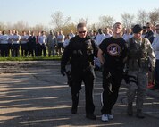 (From left) Robert Hadley and Senior Airman Jedidiah Polk, from the 319th Security Forces Squadron, simulate escorting Senior Airman Caleb Green, 319th Security Forces Squadron desk sergeant,  to jail, who volunteered to play the role of an irresponsible driver during  a simulated vehicle crash caused by someone driving under the influence for Wingman Day held on May 22, 2014, on Grand Forks Air Force Base, N.D. The Wingman Day simulations and demos were a combined effort by multiple base agencies, who intended to provide the most realistic representation of the negative impacts DUI incidents can have not only on the driver, but multiple people. (U.S. Air Force photo/Senior Airman Zachiah Roberson)