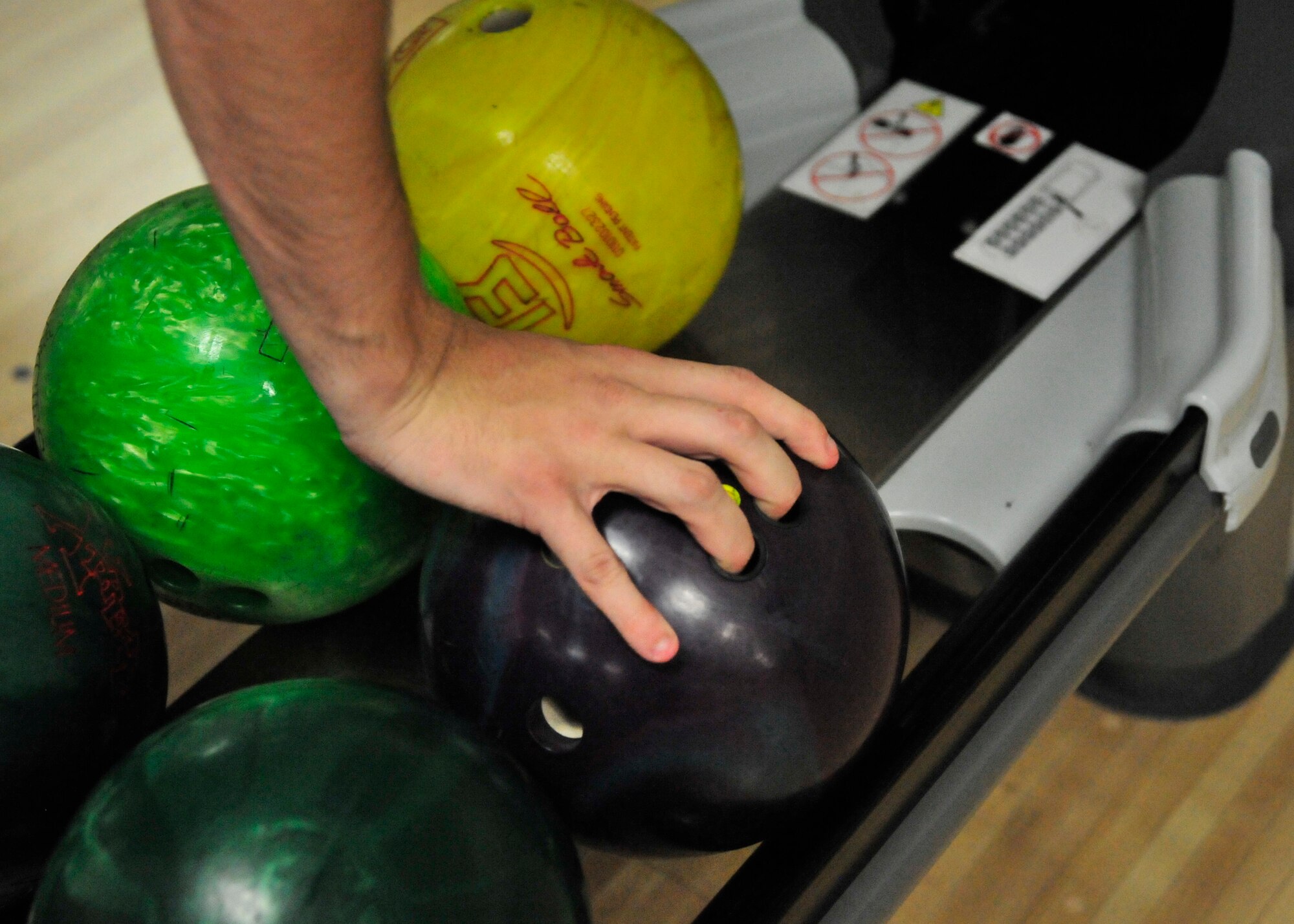 A Team Dover Airman picks his ball of choice to use during a bowling competition during Wingman Day May 22, 2014, at the Eagle Lanes Bowling Center on Dover Air Force Base, Del. Teams were limited to 4 people and the total cumulative score for the team got recorded as the team score. (U.S. Air Force photo/Staff Sgt. Elizabeth Morris)