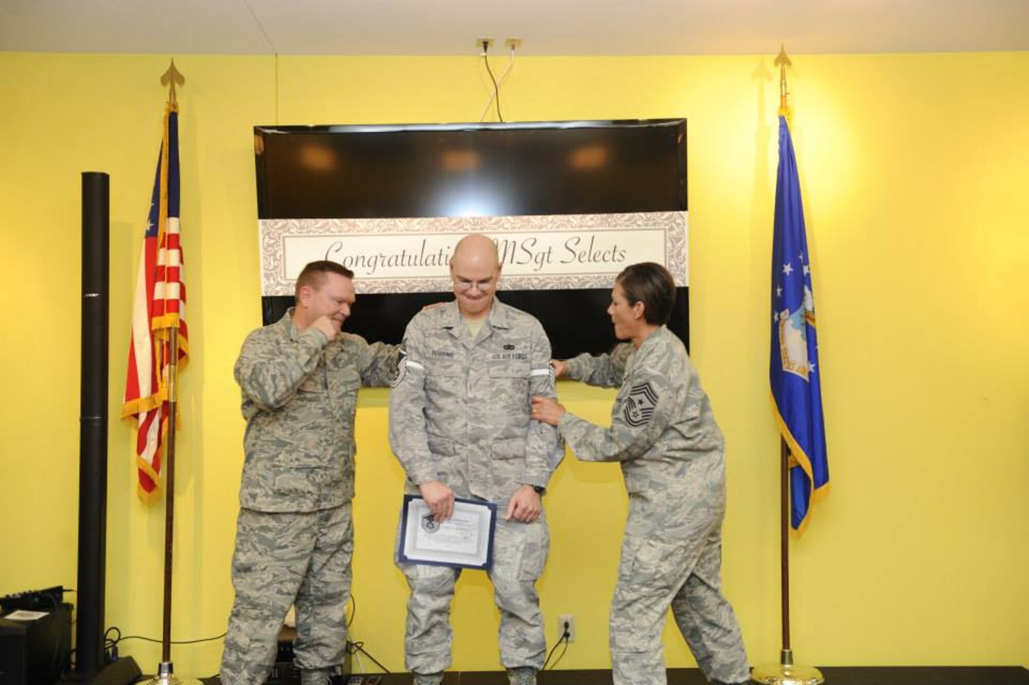 Brig. Gen. Samuel "Bo" Mahaney, Air Reserve Personnel Center commander, and Chief Master Sgt. Ruthe Flores, ARPC command chief, punch master sergeant stripes on Tech. Sgt. Eric Robbins, ARPC privacy act manager, during Team Buckley's master sergeant release party May 22. (U.S. Air Force photo by Airman 1st Class Samantha Saulsbury)