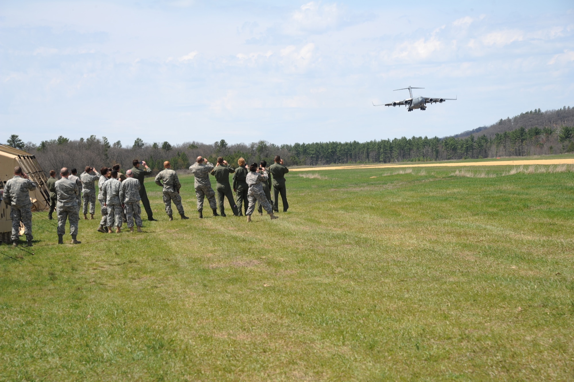 Distinguished visitors pull out mobile phones to take photos of a 445th Airlift Wing C-17 Globemaster III landing during a tour of the Young Air Assault Strip on May 10, 2014 during exercise Patriot Warrior at Fort McCoy, Wis. United States military reserve components from all branches participate in combined exercises Patriot Warrior, Global Medic, Diamond Saber and CSTX in preparation for upcoming deployments in joint environments. (U.S. Air Force photo by Master Sgt. Francisco V. Govea II/ Released)  