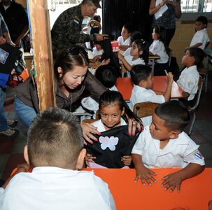 Iris Medina, Joint Task Force-Bravo civil military affairs, gives a Honduran girl a new back pack full of school supplies at the Carlos Flores Kindergarten.  Joint Task Force-Bravo, non-government organizations Clean the World, Bridge Ministries and Kick for Nick Foundation, the Honduran 21st Military Police Battalion and the Honduran National Police formed a partnership to distribute soap kits, backpacks with school supplies, tooth brushes and tooth paste, soccer balls and uniforms to students at eight Tegucigalpa, Honduras schools in a two-day event, May 20-21, 2014.  The group handed out over 4,200 soap kits, 600 backpacks, 150 tooth brushes and tooth paste, and 50 soccer balls.  (Photo by U. S. Air National Guard Capt. Steven Stubbs)