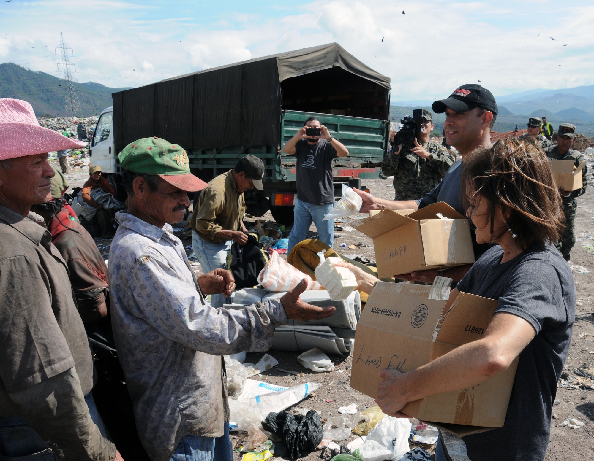 U. S. Army Lt. Col Frank Melgarejo, Joint Task Force-Bravo operations officer and Sandi Burges, Bridge Ministries founder, hand out soap kits to people at the Comayaguela Landfill.  Joint Task Force-Bravo, non-government organizations Clean the World, Bridge Ministries and Kick for Nick Foundation, the Honduran 21st Military Police Battalion and the Honduran National Police formed a partnership to distribute soap kits, backpacks with school supplies, tooth brushes and tooth paste, soccer balls and uniforms to students at eight Tegucigalpa, Honduras schools in a two-day event, May 20-21, 2014.  The group handed out over 4,200 soap kits, 600 backpacks, 150 tooth brushes and tooth paste, and 50 soccer balls.  (Photo by U. S. Air National Guard Capt. Steven Stubbs).