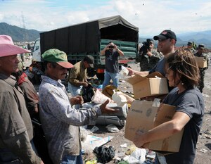 U. S. Army Lt. Col Frank Melgarejo, Joint Task Force-Bravo operations officer and Sandi Burges, Bridge Ministries founder, hand out soap kits to people at the Comayaguela Landfill.  Joint Task Force-Bravo, non-government organizations Clean the World, Bridge Ministries and Kick for Nick Foundation, the Honduran 21st Military Police Battalion and the Honduran National Police formed a partnership to distribute soap kits, backpacks with school supplies, tooth brushes and tooth paste, soccer balls and uniforms to students at eight Tegucigalpa, Honduras schools in a two-day event, May 20-21, 2014.  The group handed out over 4,200 soap kits, 600 backpacks, 150 tooth brushes and tooth paste, and 50 soccer balls.  (Photo by U. S. Air National Guard Capt. Steven Stubbs).