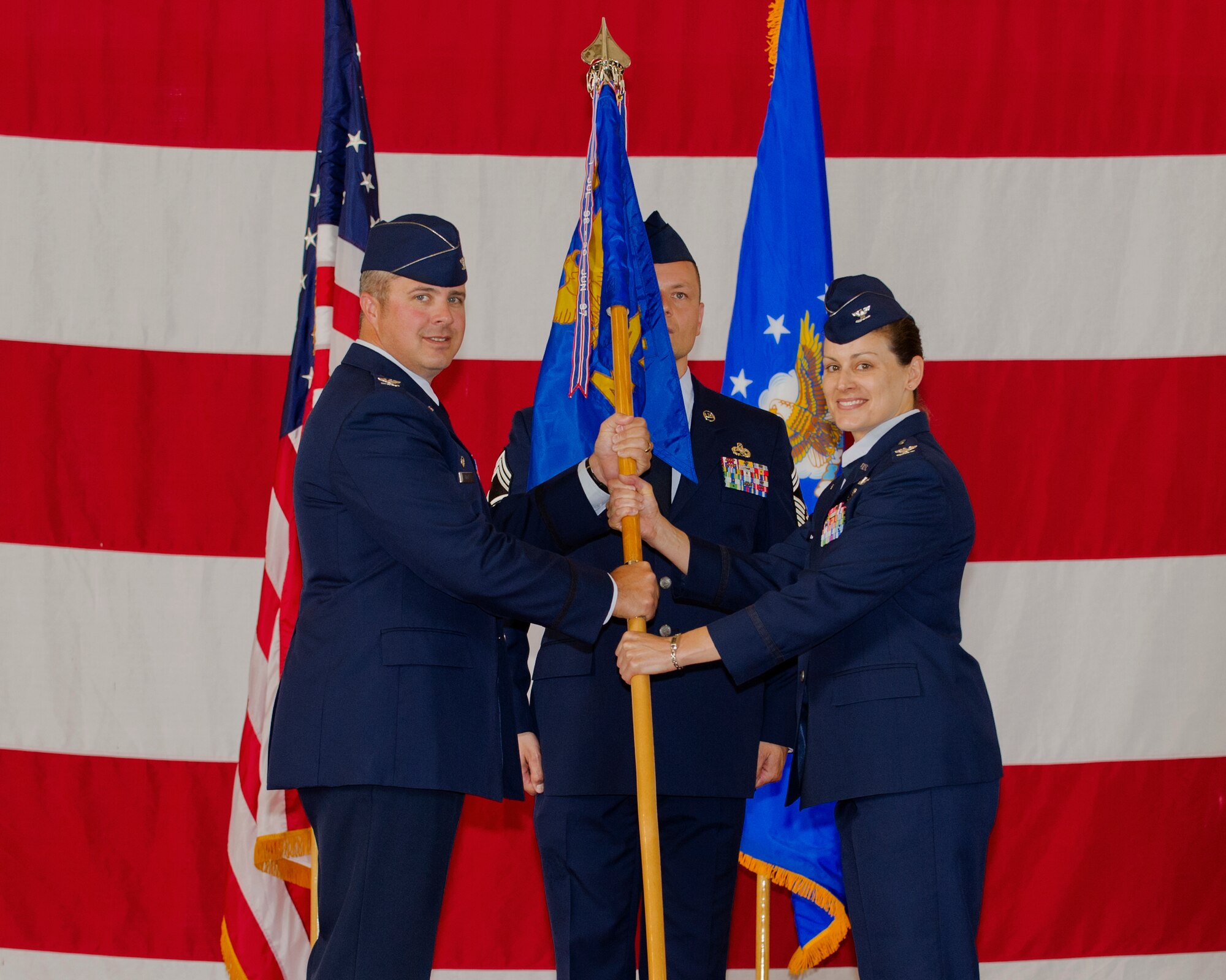 Col. David E. Graff, 325th Fighter Wing commander, passes the 325th Maintenance Group guidon to Col. Jacqueline M. Mongeon, 325th MXG commander, during a change of command ceremony May 28. Mongeon replaces Col. Curtis R. Hafer who will join the logistics staff at Air Combat Command at Joint Base Langley-Eustis, Va. (U.S. Air Force photo by Airman 1st Class Alex Echols)
