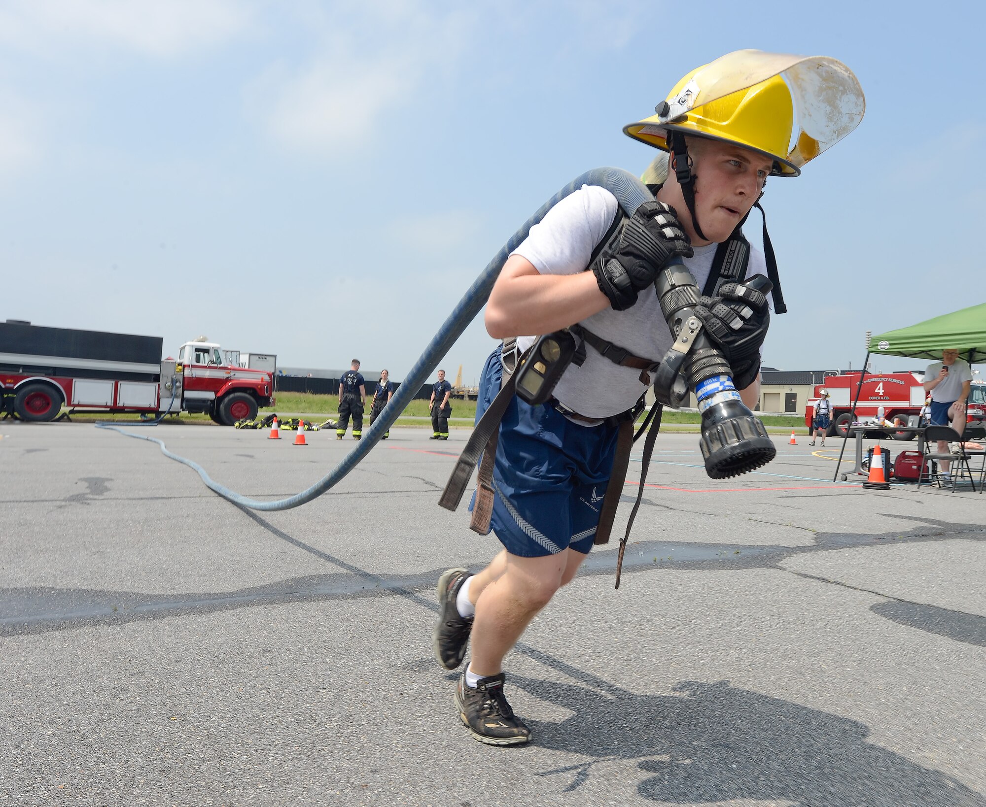 A participant in the Firefighter's Challenge drags a fire hose out to full length during the 2014 Wingman Day at Eagles Nest Park on May 22, 2014, at Dover Air Force Base, Del. Ten, four person teams participated in the fast-paced event while wearing protective equipment.