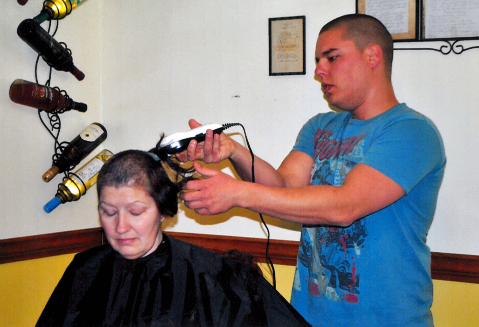 Senior Airman Steven Przyojski shaves the hair of Senior Master Sgt. Dale Pryojski after she started her chemotherapy.  (Courtesy photo/Released)