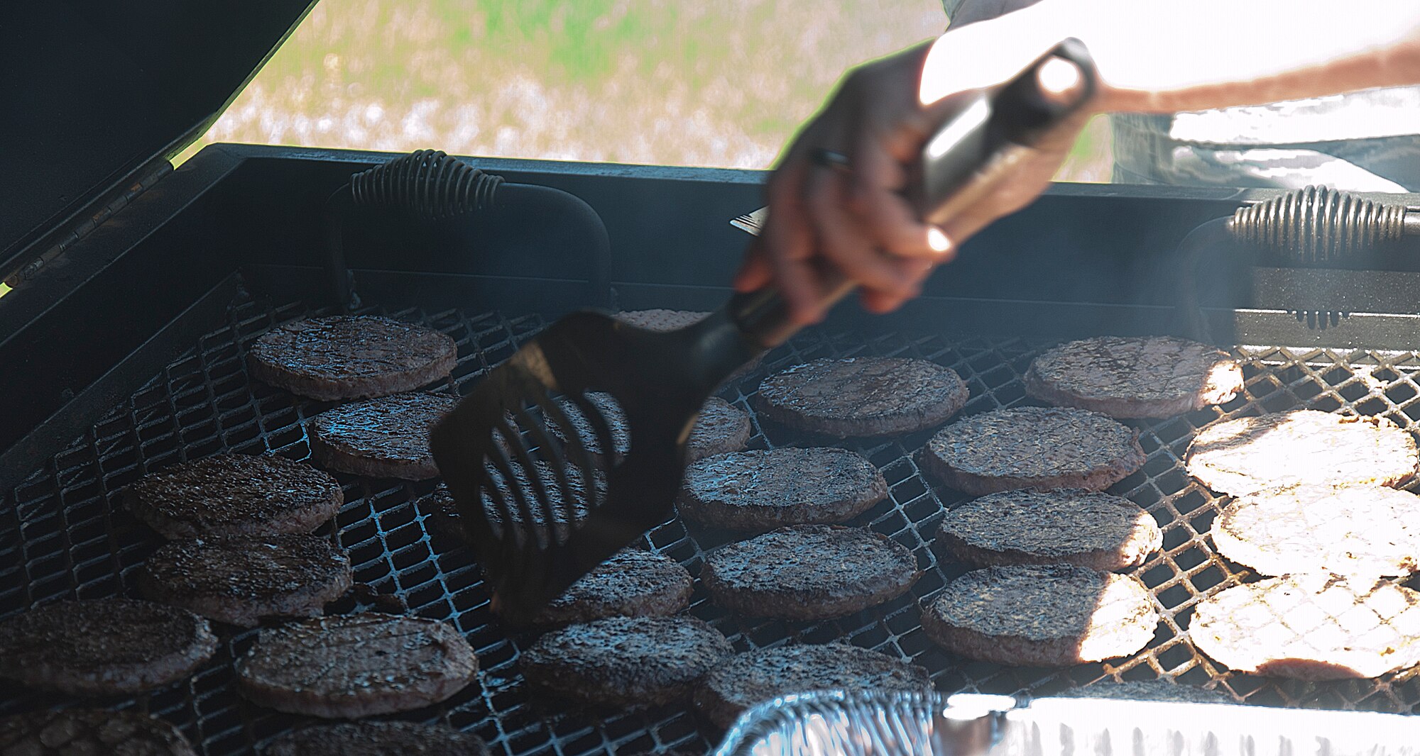 Burgers are cooked over an open flame May 27 in support of the 90th Missile Wing burger-burn fundraiser at the Fall Hall Community Center. Burgers and bratwurst were sold to help raise funds for the wing’s upcoming dining out June 13. 
