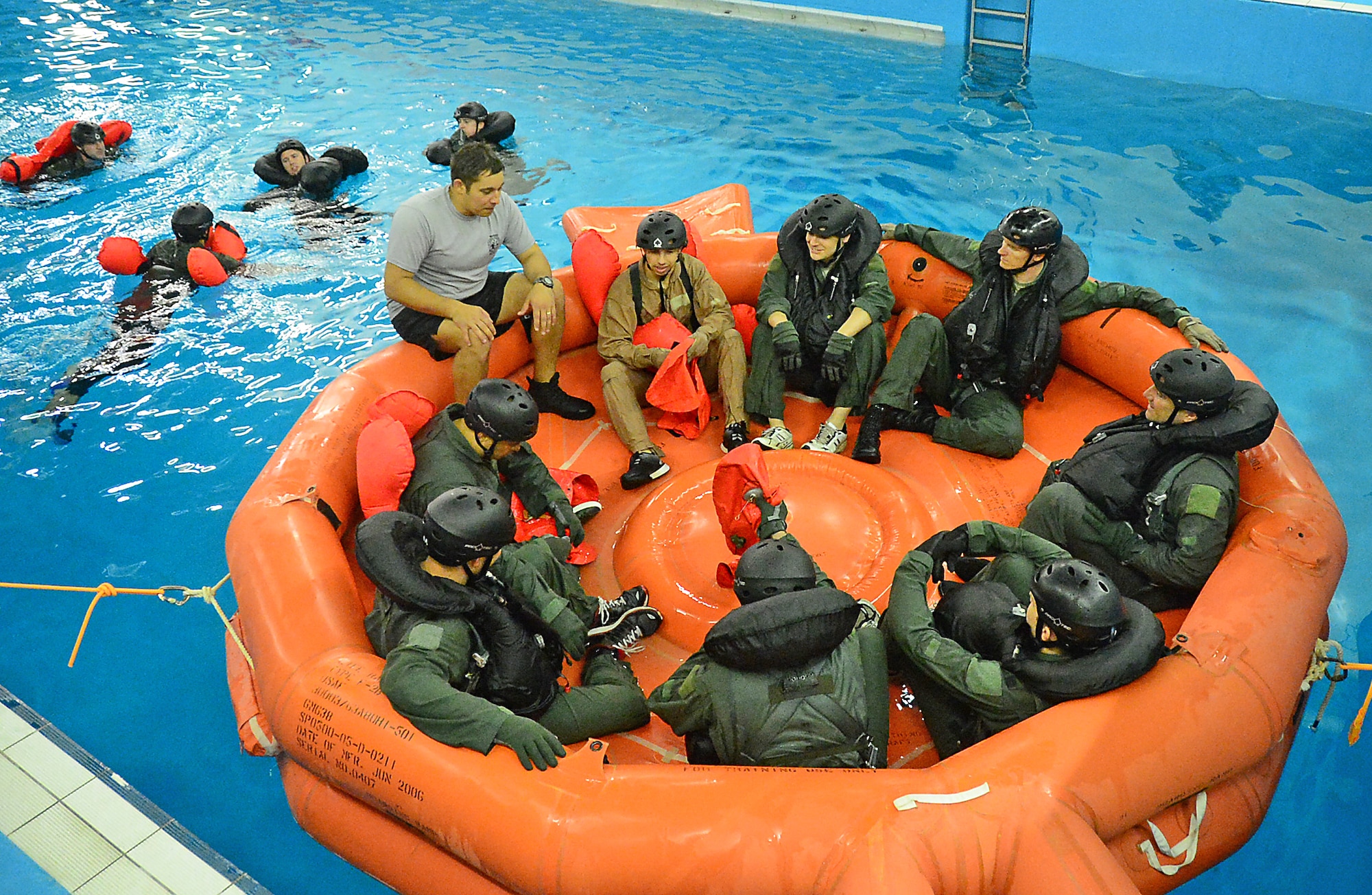 Fighter, air refueling and special operations aircrew participate in a water survival training course led by a U.S. Air Force survival training expert (grey) at the Lowestoft College pool in Lowestoft, England, May 22, 2014. The class is mandatory for aircrew operating over a body of water. Harsh sea conditions off the coast of England present a major danger and can force pilots to adjust training flights to take place in airspace over land. Ultimately, this shift may lead to increased aircraft noise heard by U.K. communities. (U.S. Air Force photo by Airman 1st Class Erin O’Shea/Released)
