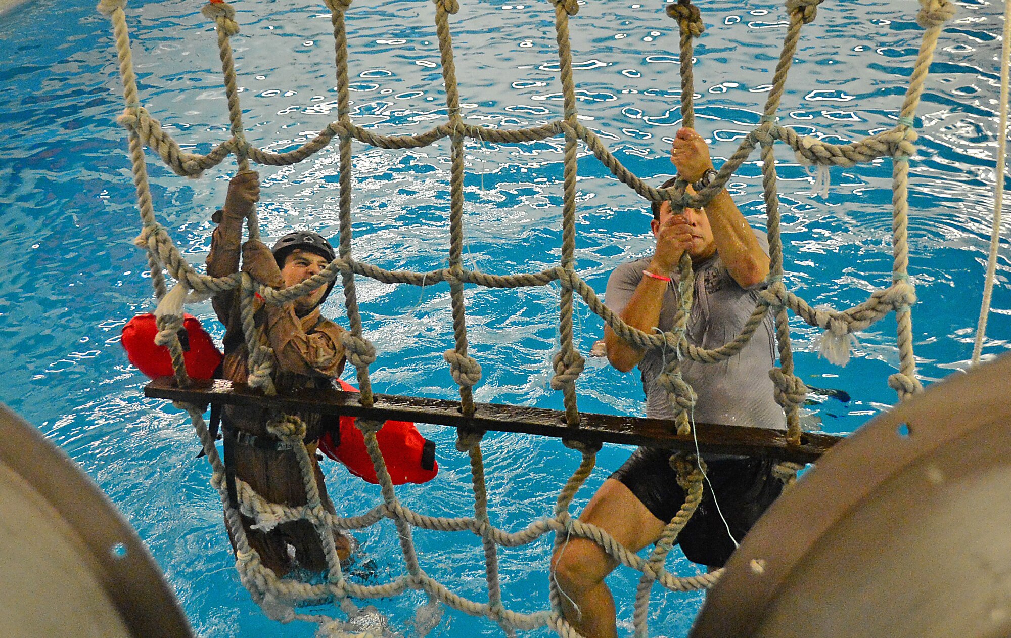 A U.S. Air Force Survival, Evasion, Resistance and Escape instructor (right) demonstrates the proper use of a recovery net commonly found on ships, to Airman 1st Class Trevor McBride, 48th Fighter Wing Public Affairs photojournalist, during a water survival training course at the Lowestoft College pool in Lowestoft, England, May 22, 2014. The class prepared personnel for dangerous environments created by harsh weather conditions over water. The 48th Fighter Wing’s strategic, European-based location enables the unit to support U.S. Air Forces in Europe’s “Forward, Ready, Now” posture by providing worldwide, responsive, combat airpower. (U.S. Air Force photo by Airman 1st Class Erin O’Shea/Released)