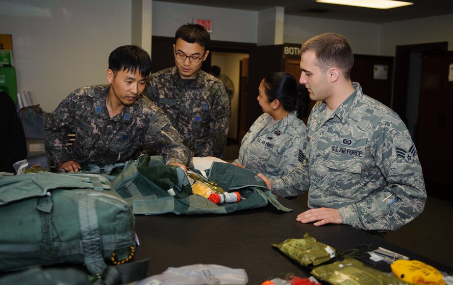 Tech. Sgt. Evelinda Lombard, 8th Operations Support Squadron Aircrew Flight Equipment hub section NCO in-charge, and Senior Airman Zachary Hansen, 8th OSS AFE journeyman, listen to Republic of Korea AFE technicians during a joint training session at Kunsan Air Base, ROK, May 21, 2014. The 8th OSS AFE office hosted several Republic of Korea AFE and maintenance Airmen to share knowledge on how and what to pack for ROKAF’s first F-16 Fighting Falcon flight to exercise Red Flag Alaska. (U.S. Air Force photo by Senior Airman Armando A. Schwier-Morales/Released)