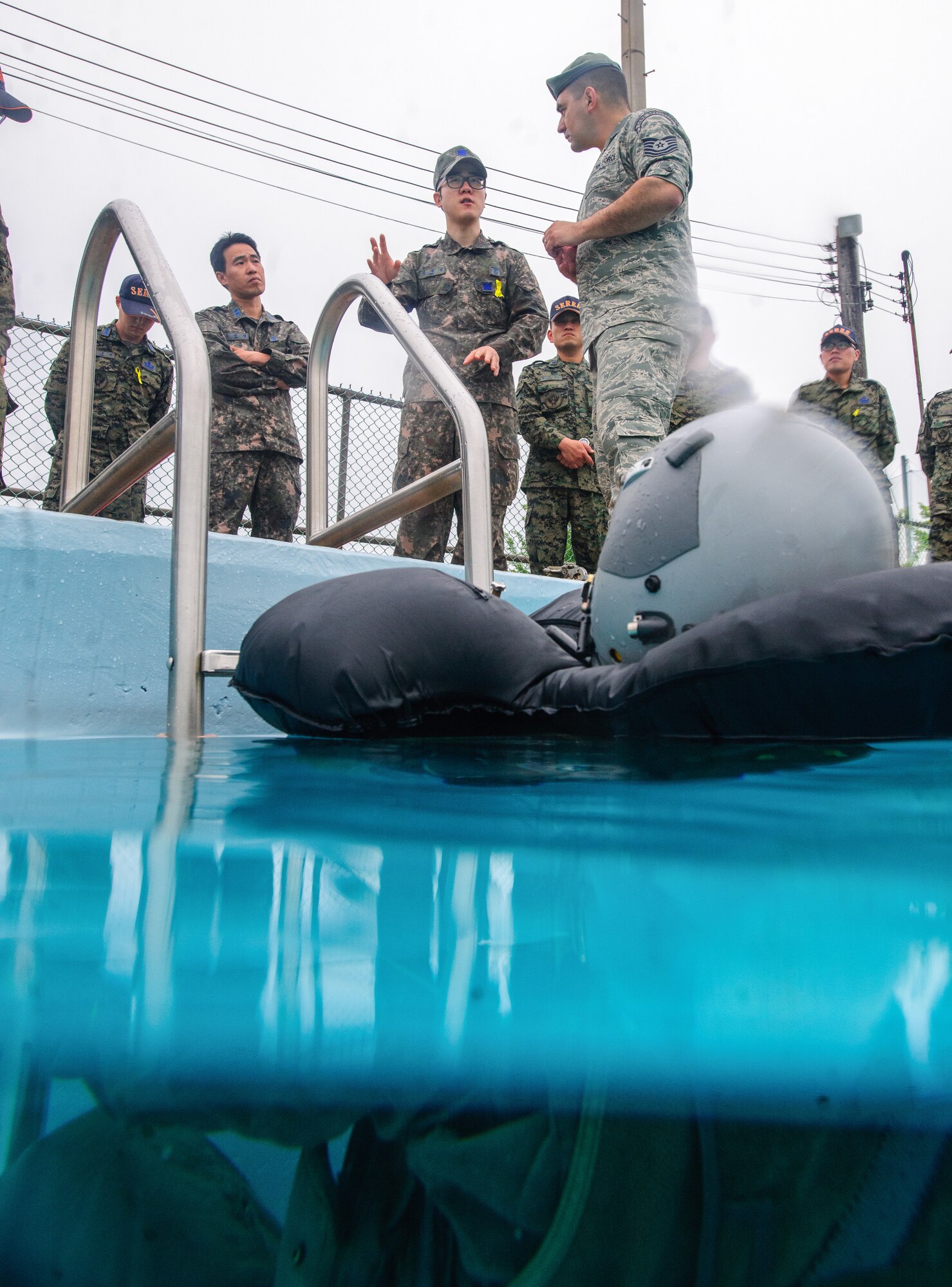 Tech. Sgt. Joseph Monreal, 51st Operations Support Squadron SERE specialist, listens to Republic of Korea SERE instructors at Kunsan Air Base, Republic of Korea, May 20, 2014. Douge and the SERE team hosted the Republic of Korea SERE instructors to share knowledge on water survival training for pilots from both nations.  (U.S. Air Force photo by Senior Airman Armando A. Schwier-Morales/Released)