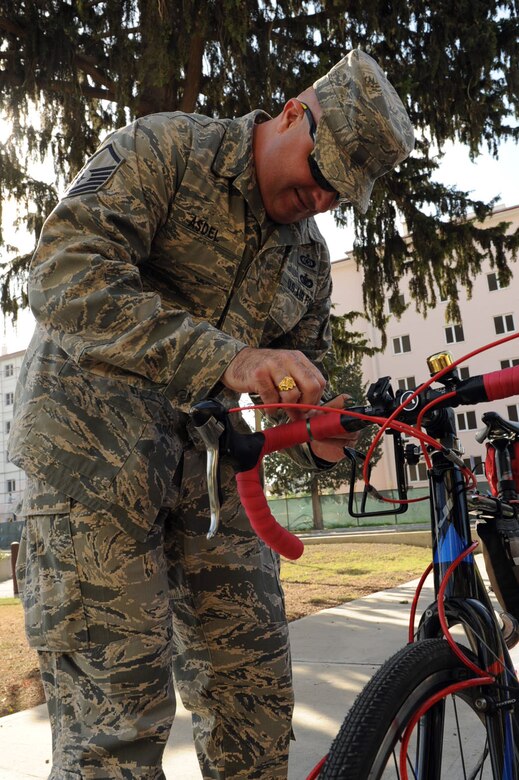 Master Sgt. Michael Asdel, 39th Air Base Wing ground safety manager, ties a green safety ribbon to a bicycle May 20, 2014, Incirlik Air Base, Turkey. Asdel is the head of the Green Ribbon campaign for personal risk management awareness on Incirlik. (U.S. Air Force photo by Staff Sgt. Eboni Reams)