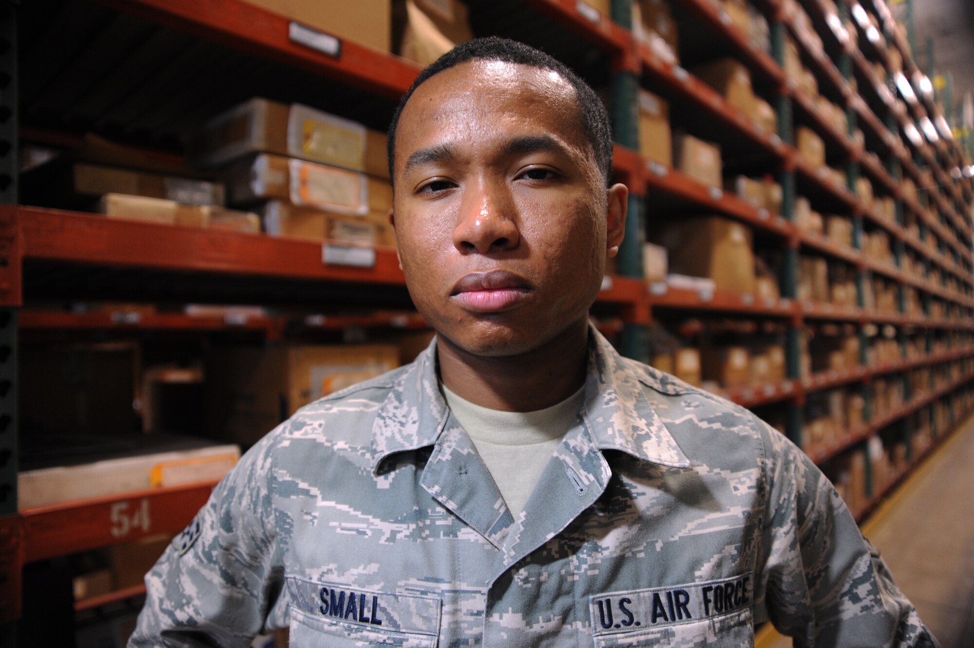 Senior Airman Arsenio Small, 35th Logistics Readiness Squadron inspections manager, stands before shelves full of base assets within the LRS warehouse at Misawa Air Base, Japan, May 27, 2014. Small was selected as the 35th LRS's Wild Weasel of the Week. (U.S. Air Force photo/Staff Sgt. Alyssa C. Wallace) 