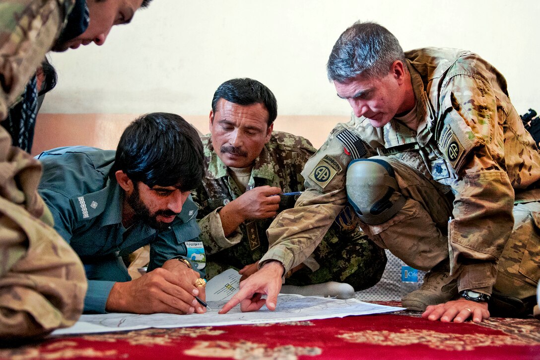 U.S. Army Lt. Col. Praxitelis Vamvakias, right, discusses combined operations with Lt. Abdul Roulf, Qara Bagh district police chief, lower left, and Afghan army Col. Mosafer, center, during a security meeting at the Qara Bagh district's center in Afghanistan's Ghazni province, July 16, 2012. Vamvakias commands the 82nd Airborne Division's 2nd Battalion, 504th Parachute Infantry Regiment, 1st Brigade Combat Team.  
