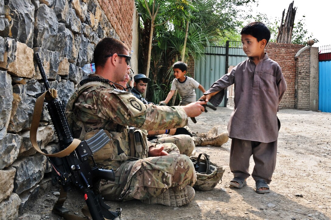 U.S. Army 1st Lt. Greg Lins greets a local Afghan boy inside a qalat of a girls' school in the village of Mangas in Afghanistan's Khowst province, July 7, 2012. Lins, a platoon leader, is assigned to the 2nd Battalion (Airborne), 377th Field Artillery Regiment.  
