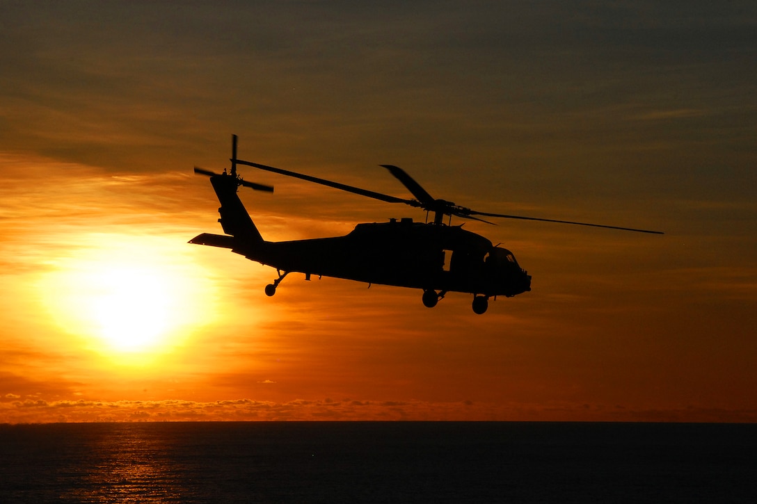 An MH-60S Sea Hawk helicopter approaches the USNS Amelia Earhart at sunrise in the Pacific Ocean, July 8, 2012, after delivering supplies to the USS George Washington during a vertical replenishment mission.  
